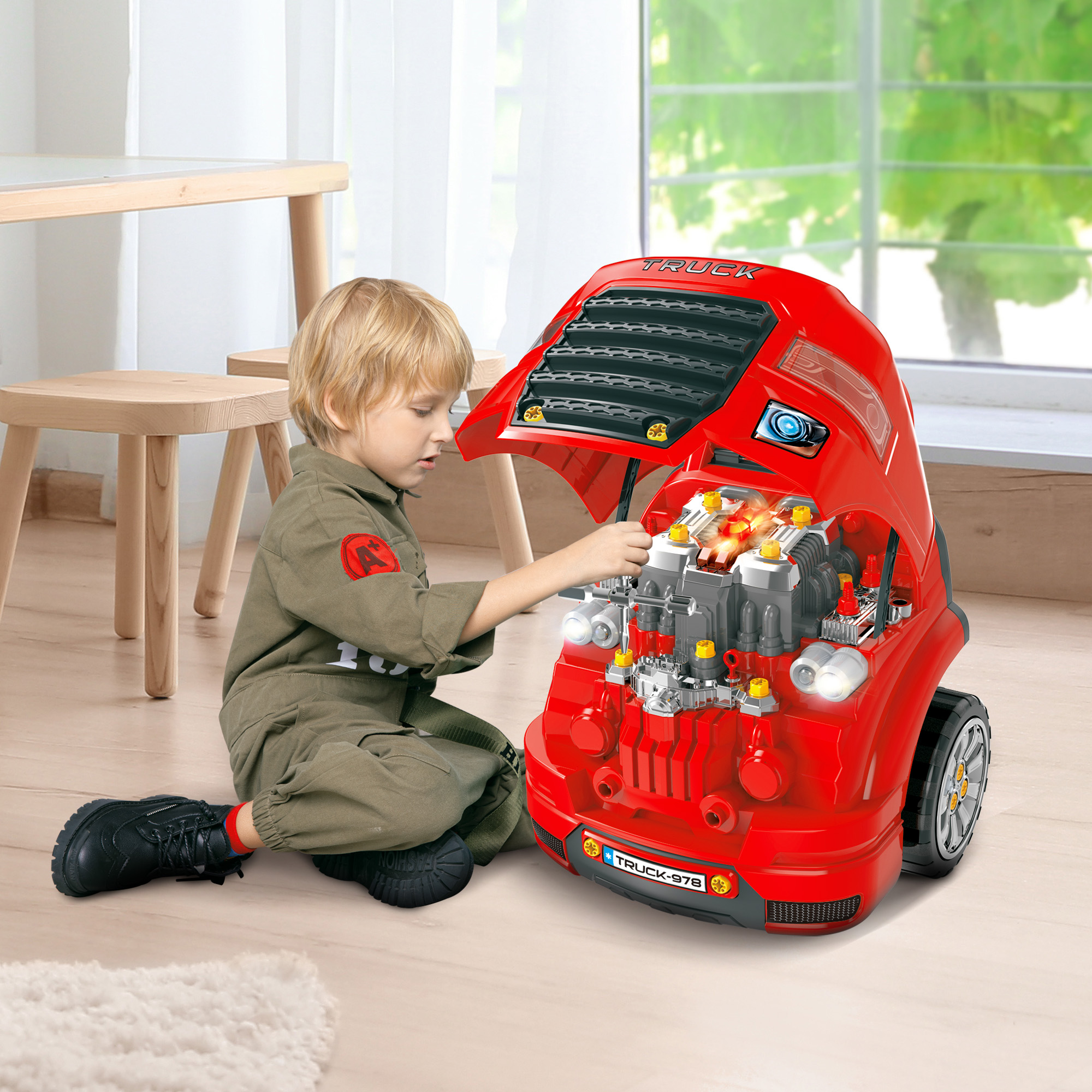Un niño jugando con un camión de juguete rojo, abriendo el capó. Suelo de madera, alfombra blanca.