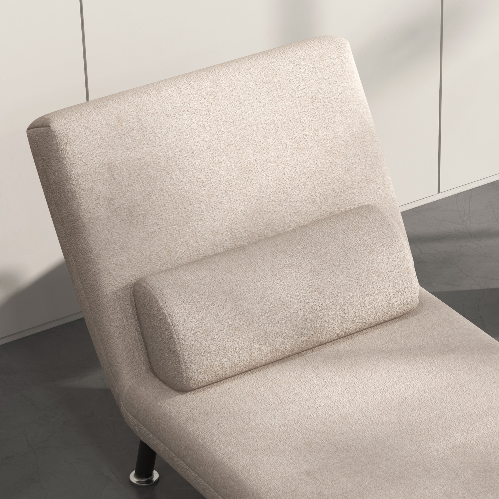 Una chaise longue beige con un cuscino cilindrico. È accanto a un muro bianco.