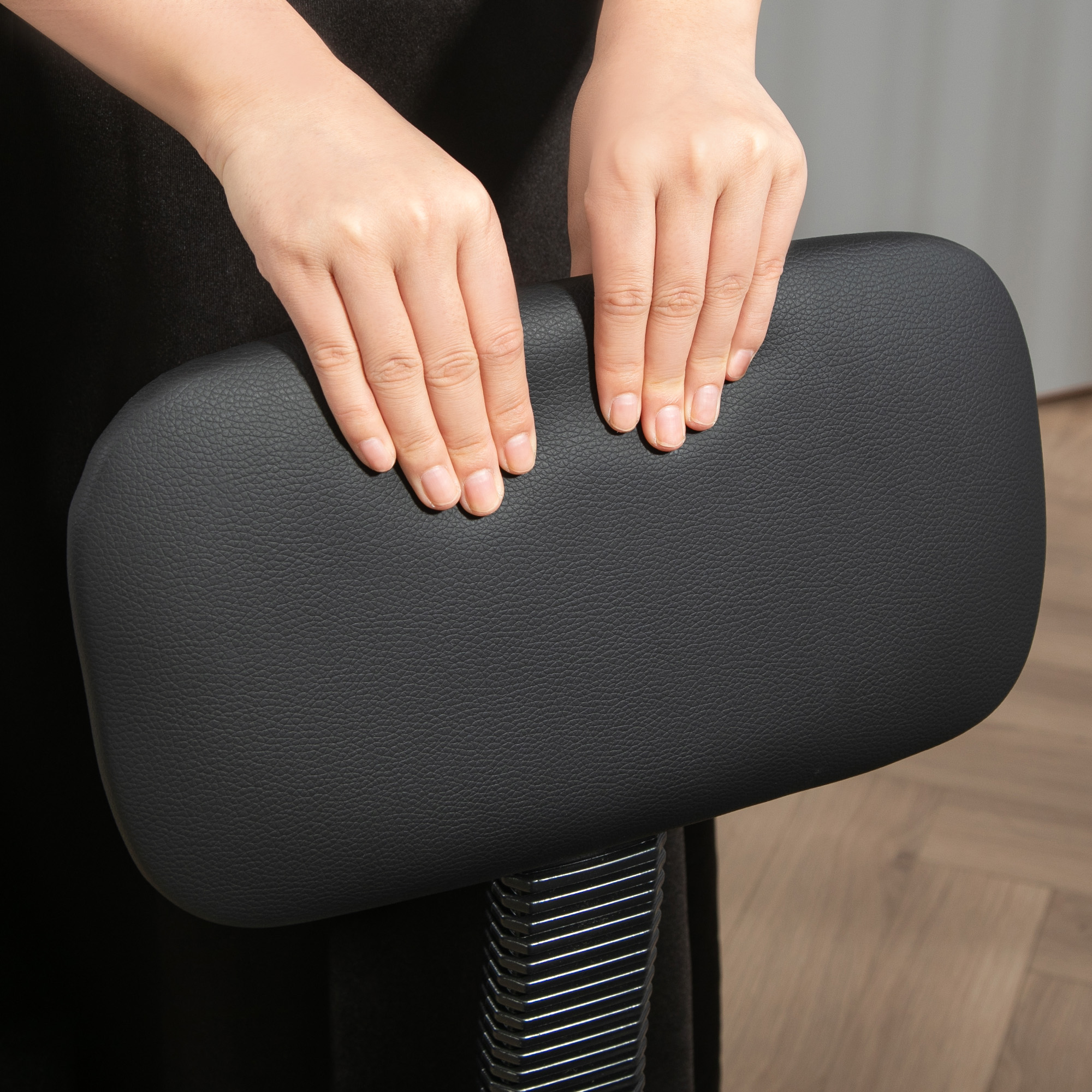 Mani che tengono un sedile in pelle nera, forse per una sedia. Le mani sono visibili, che tengono il sedile.