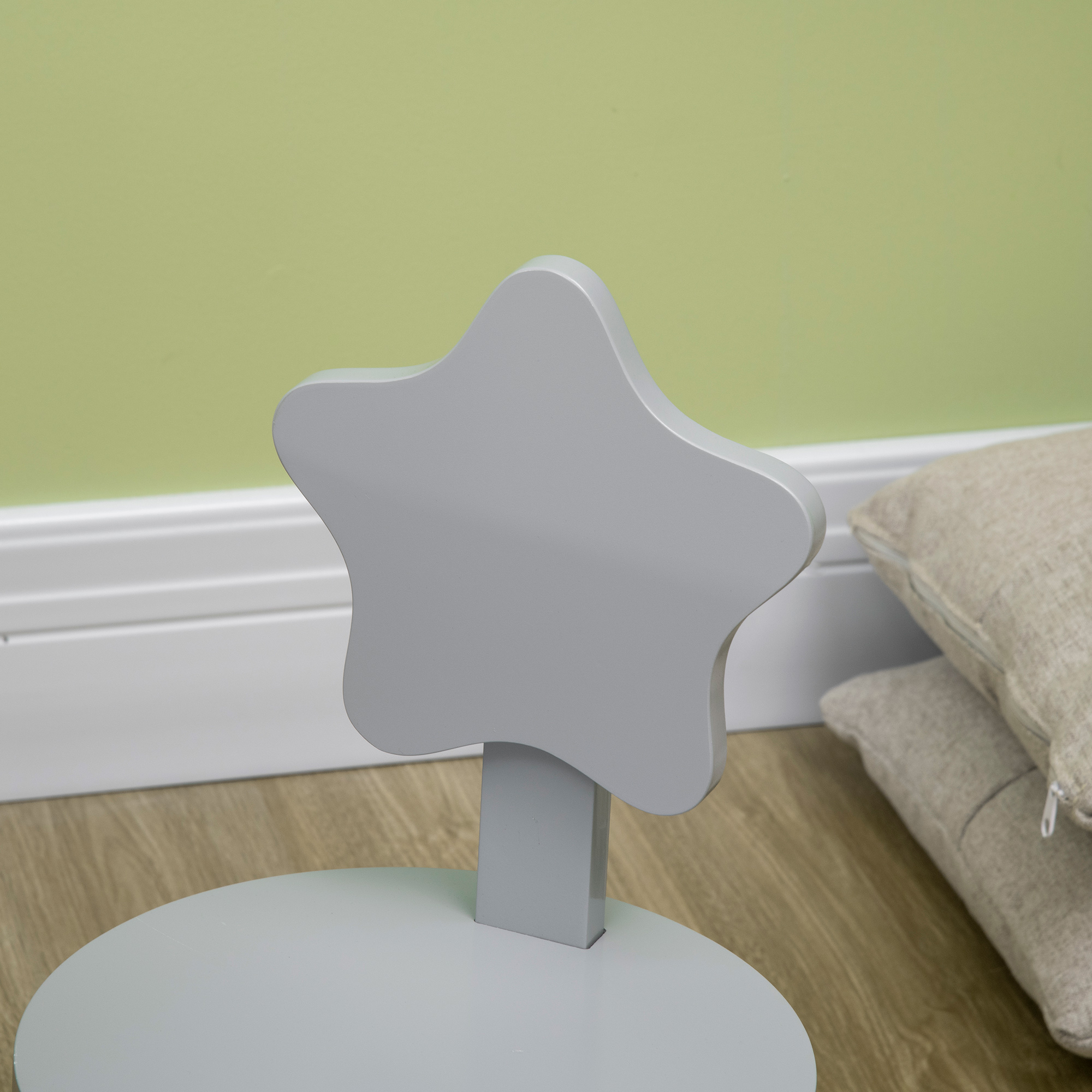 Oggetto grigio a forma di stella su un supporto. Pavimento in legno, cuscini e muro sullo sfondo.