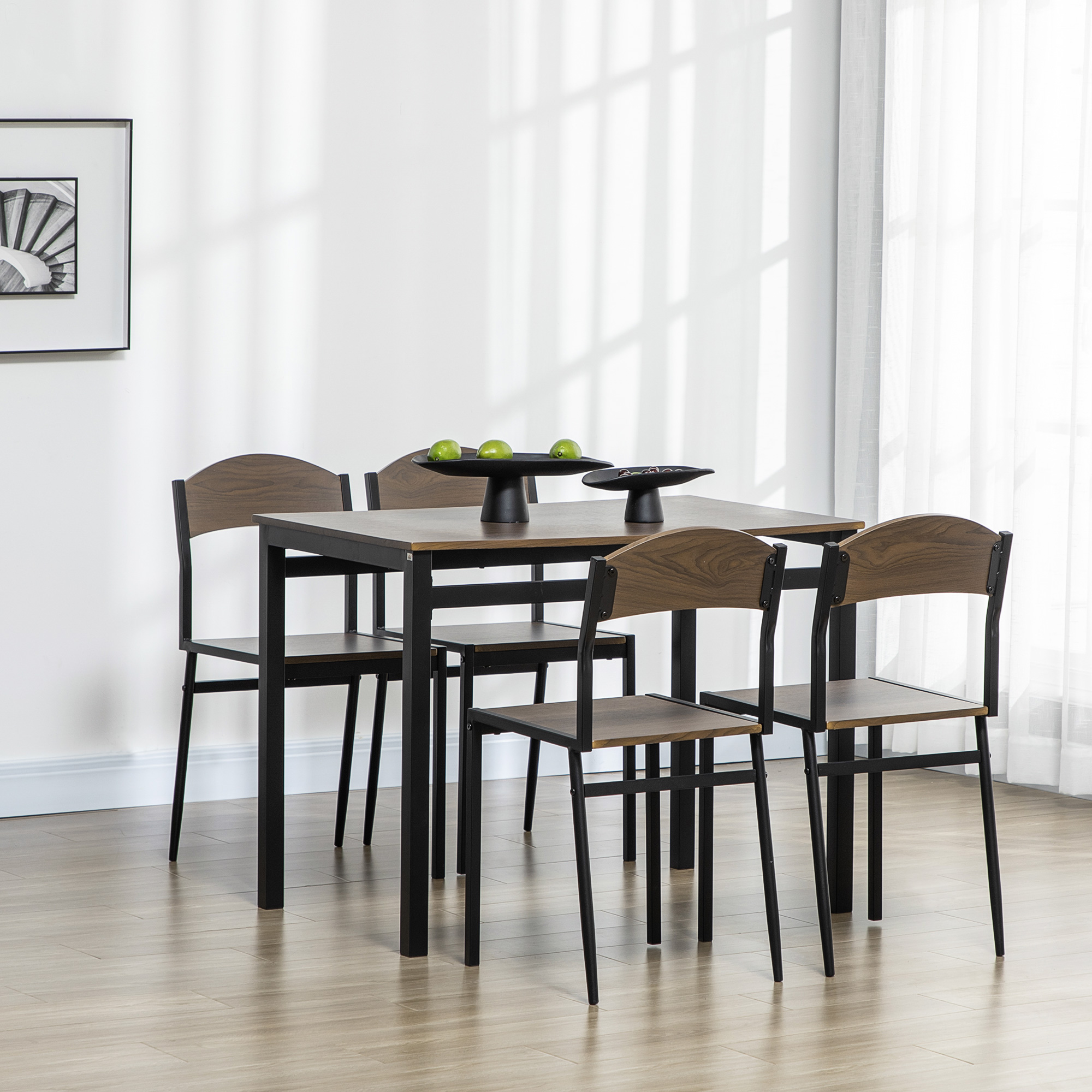 Una sala da pranzo con tavolo e sedie. Il tavolo ha un piano in legno e gambe nere. Quattro sedie attorno al tavolo.