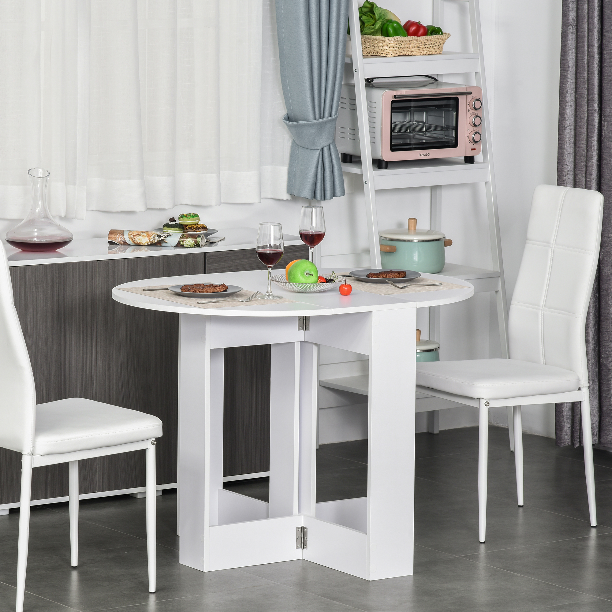 Tavolo pieghevole bianco con tovaglia. Sedie bianche e un armadio. Sfondo cucina.