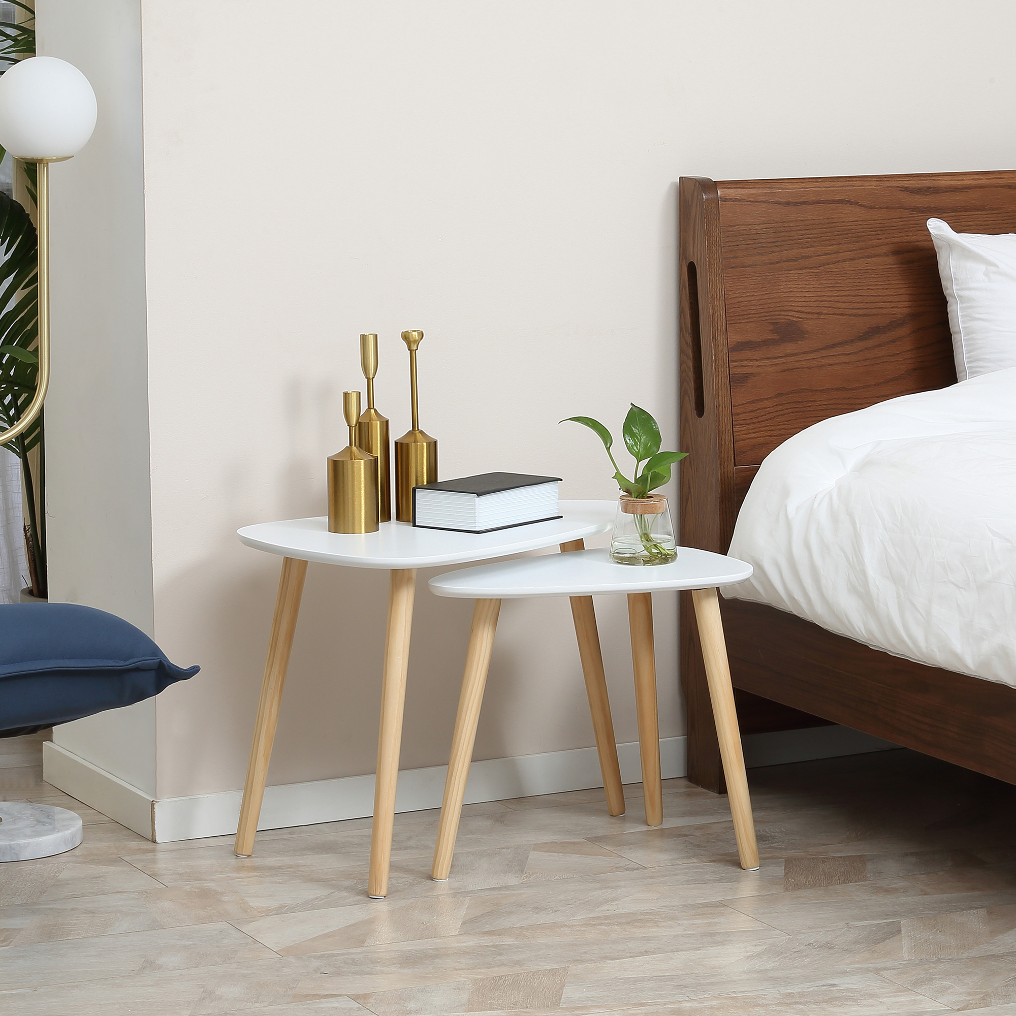 Due comodini bianchi con gambe in legno, in una camera da letto, con decorazioni.
