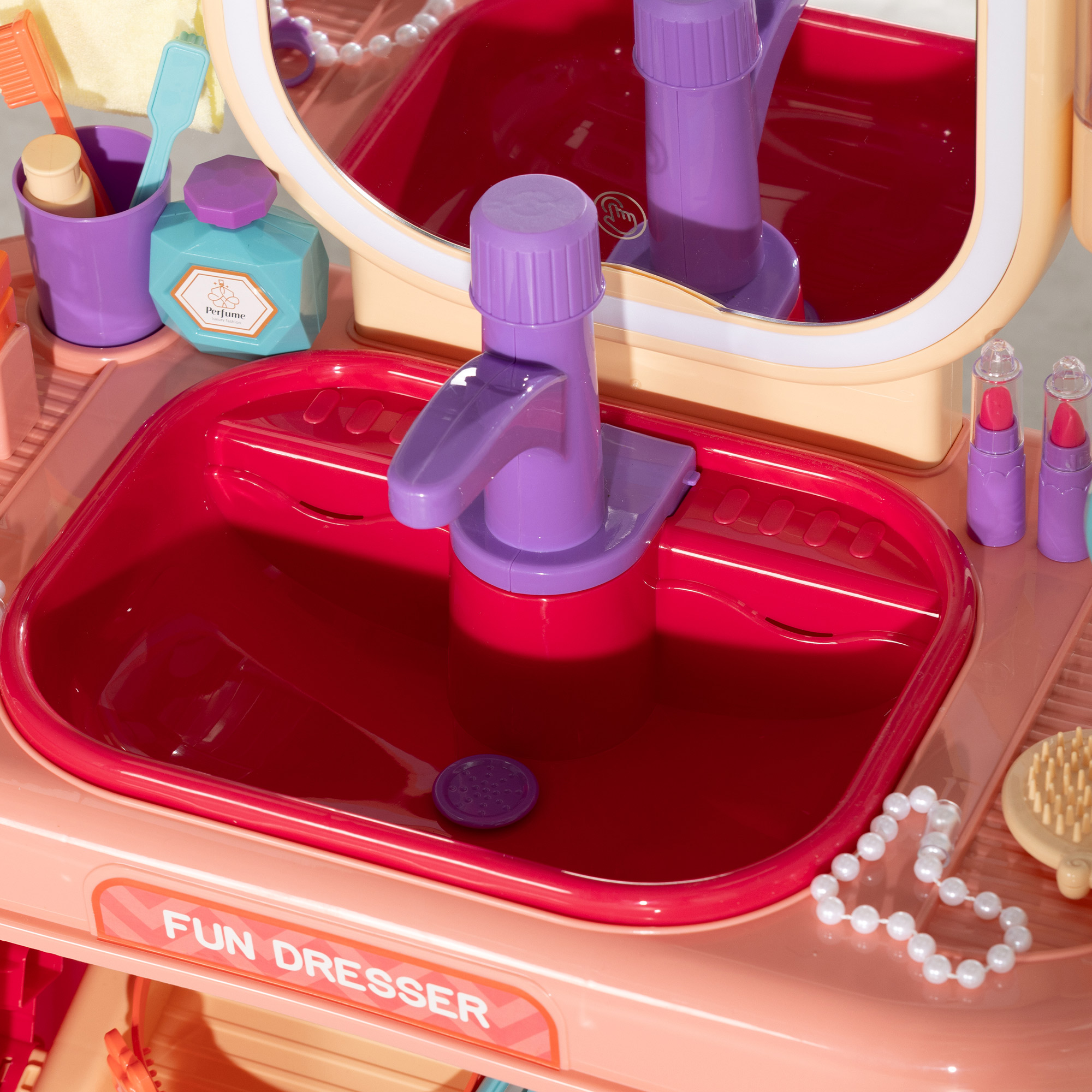 Un mobile toeletta giocattolo rosa per bambini con lavandino, specchio e accessori di bellezza.