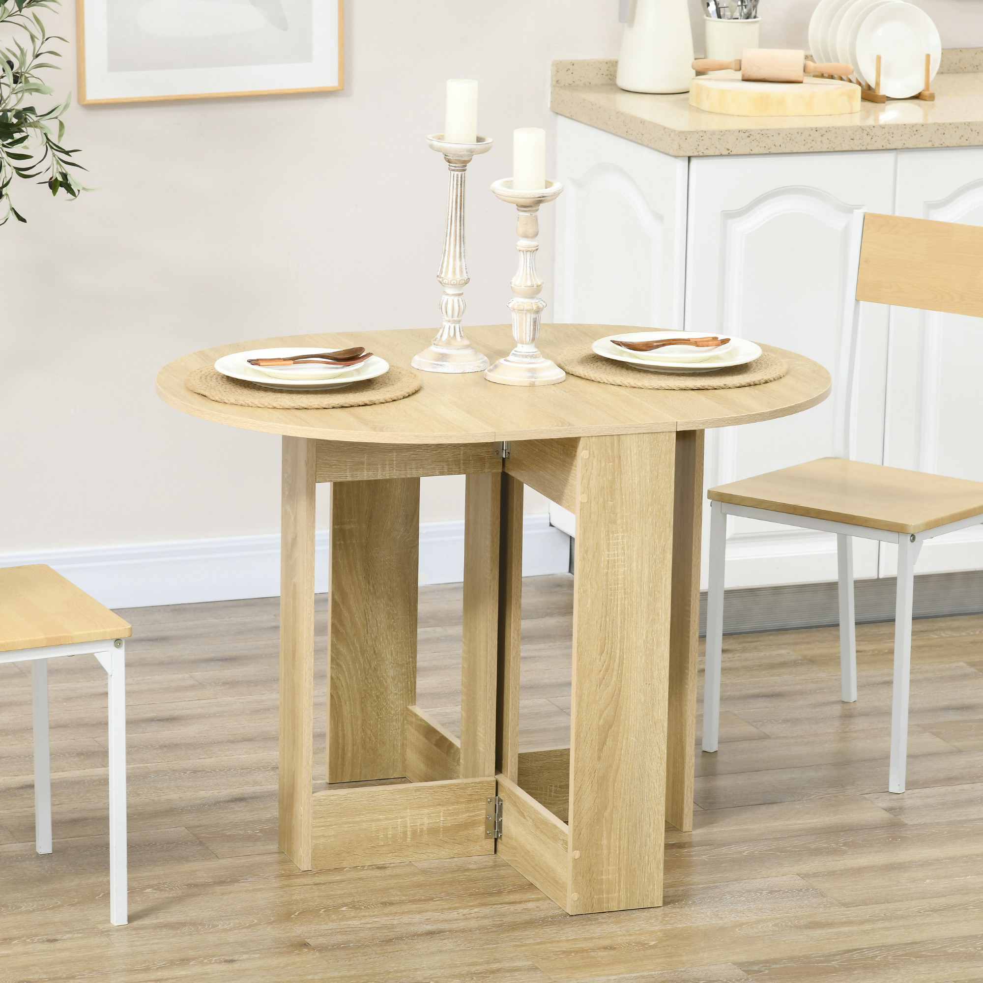 Tavolo da pranzo rotondo in legno con due coperti e candelabri su sfondo cucina bianca.