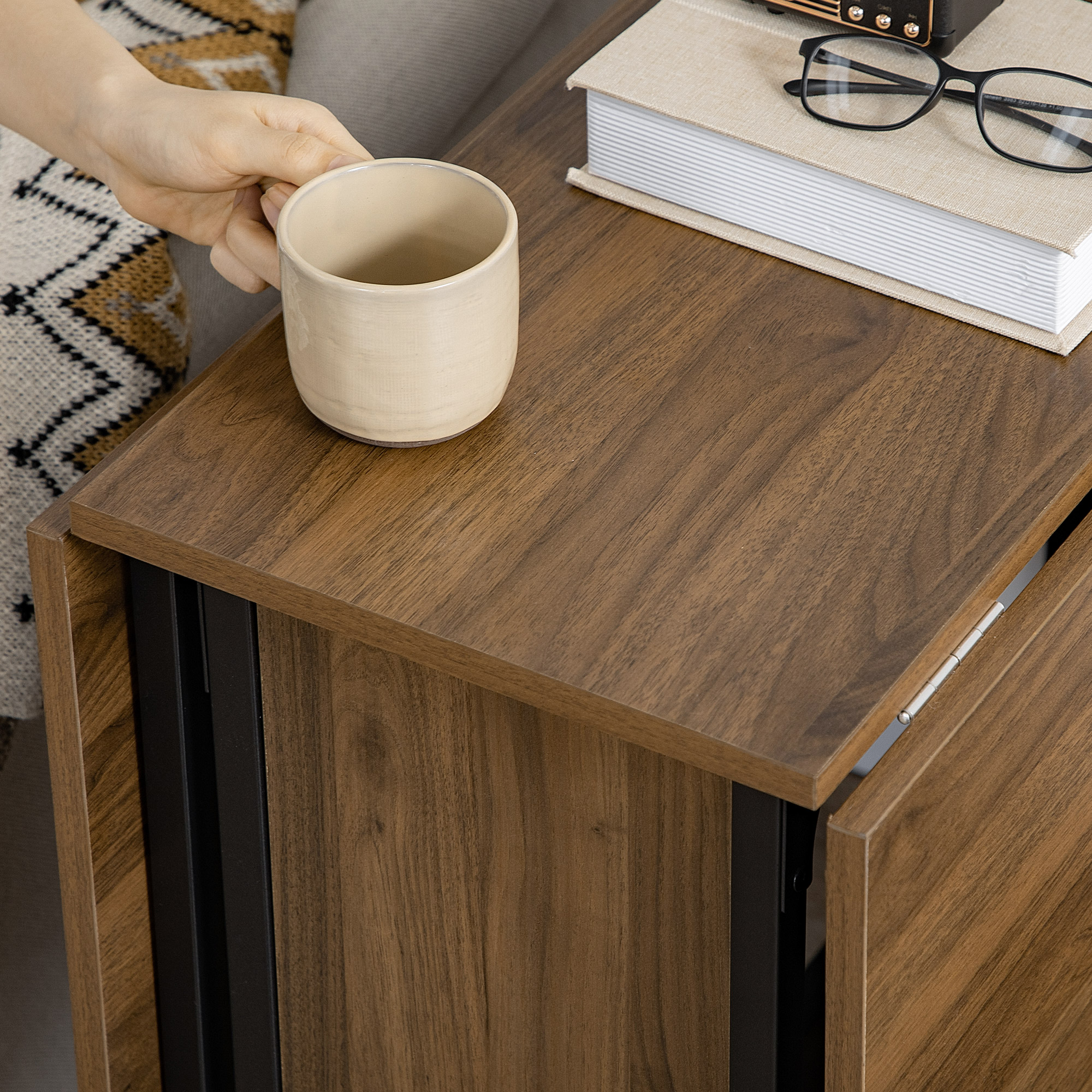 Una mano che tiene una tazza beige su un tavolo di legno.