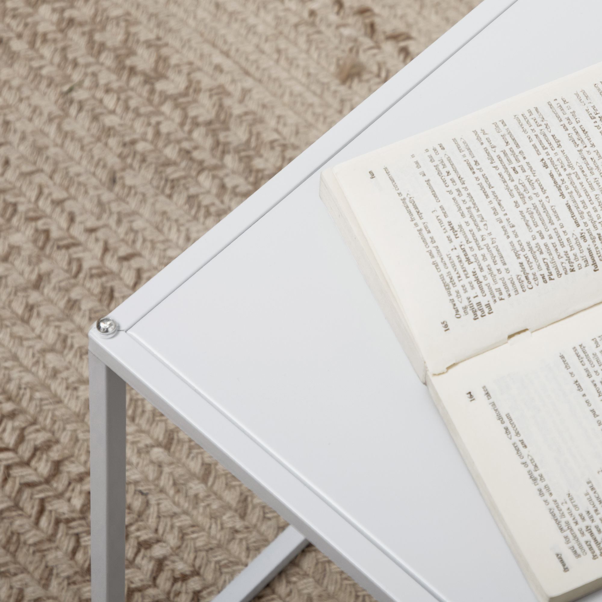 Un tavolino bianco con un libro aperto, che mostra i numeri di pagina e il testo.