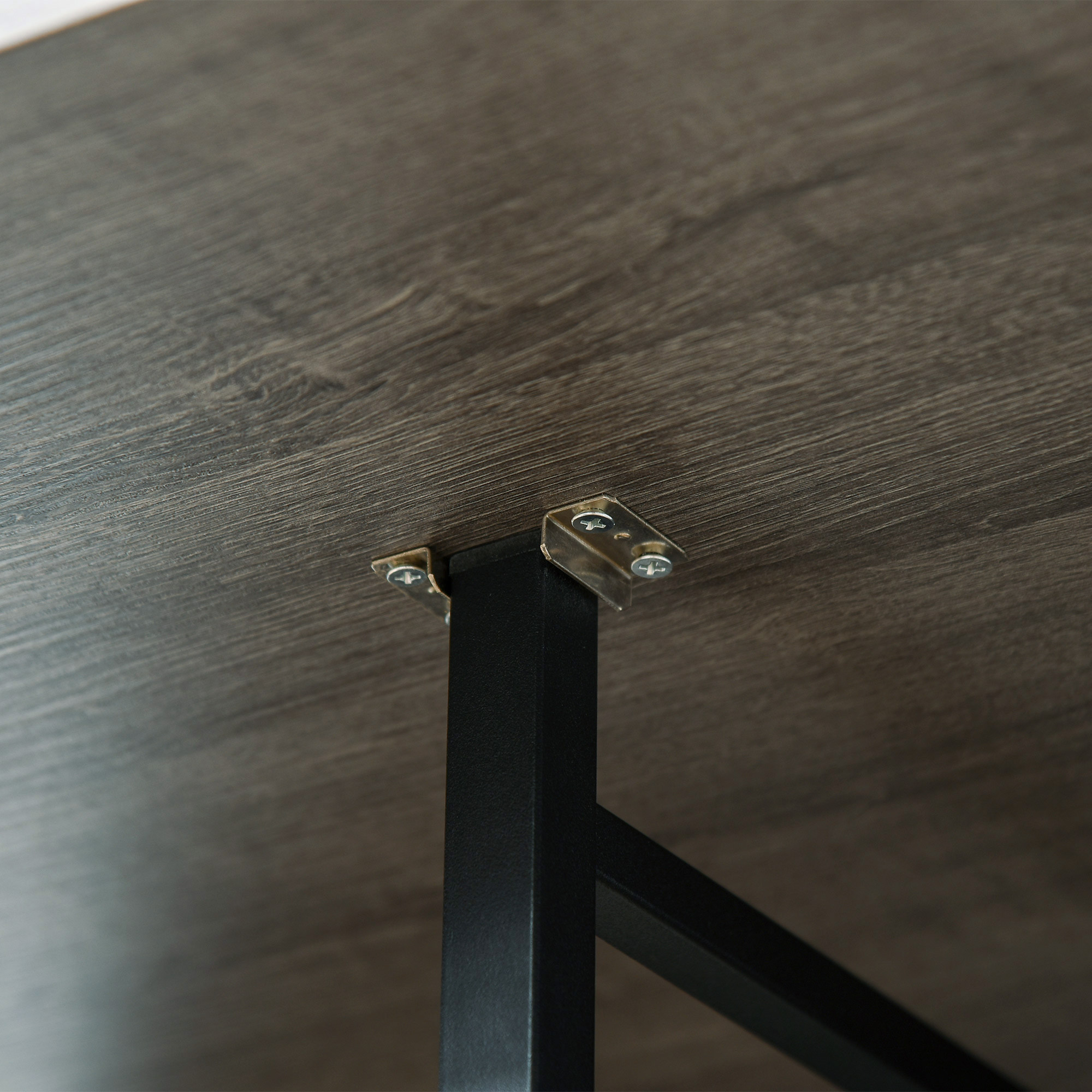 Primo piano del lato inferiore di un tavolo di legno, che mostra staffe metalliche e un telaio.