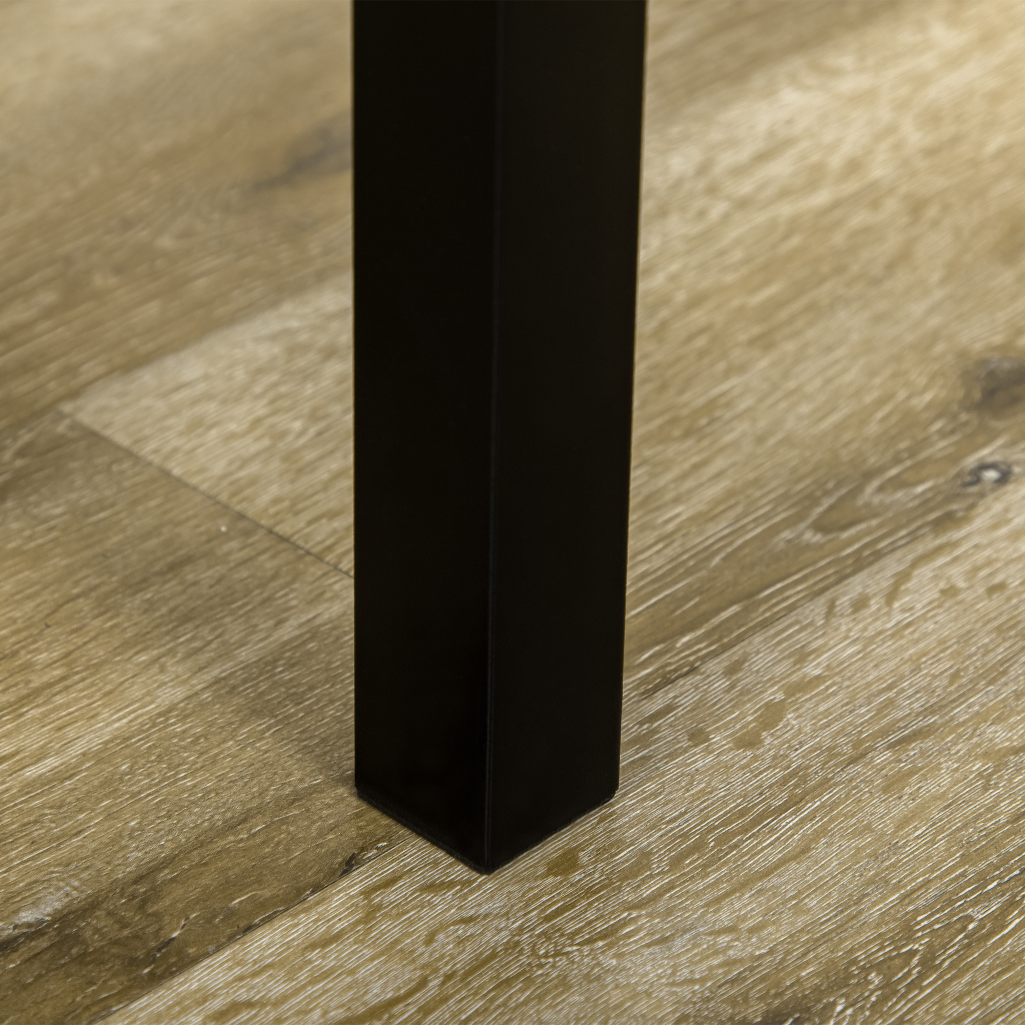 Primo piano di una gamba di tavolo nera su un pavimento in legno.