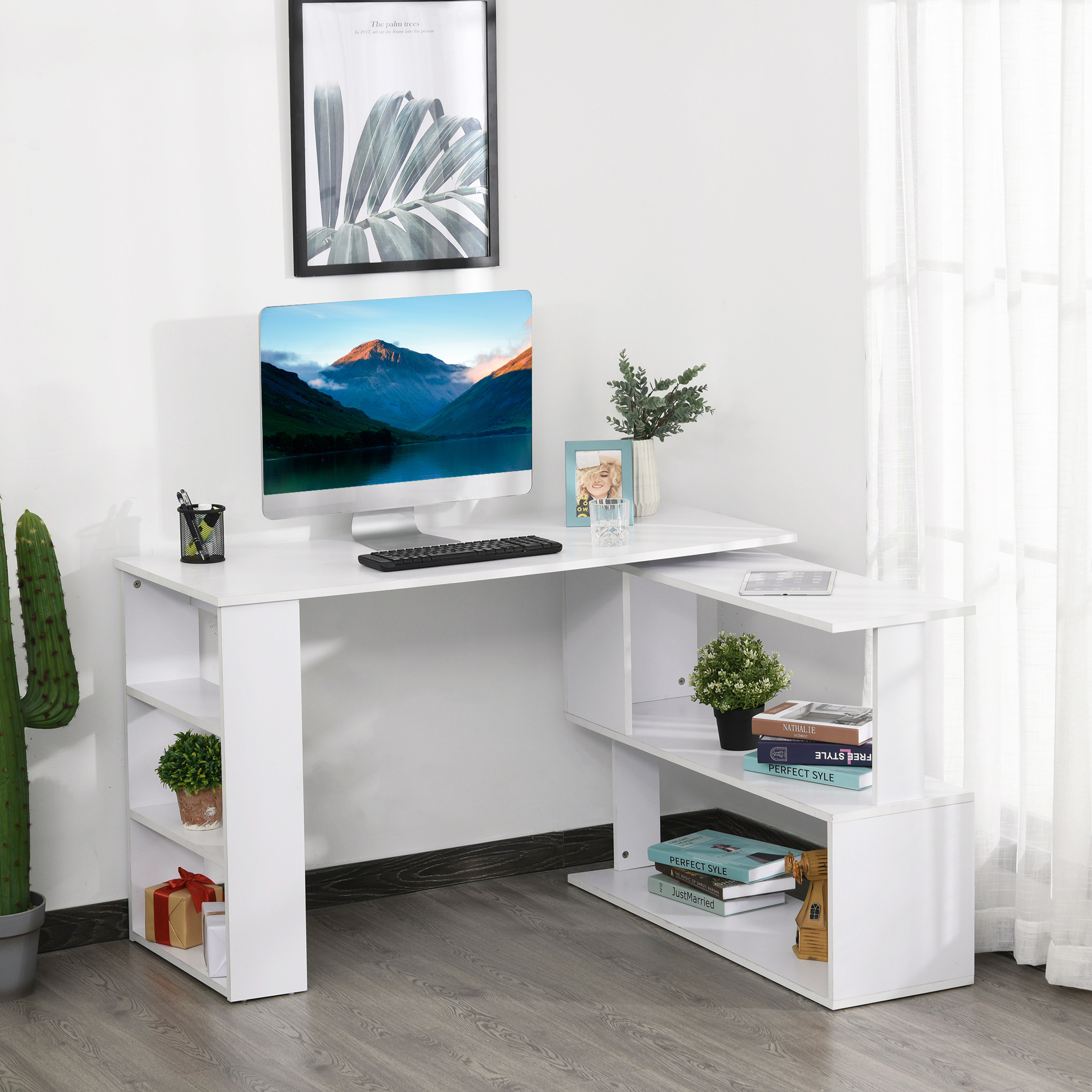 Una scrivania bianca con computer, libri e decorazioni. Scaffali e finestra visibili.