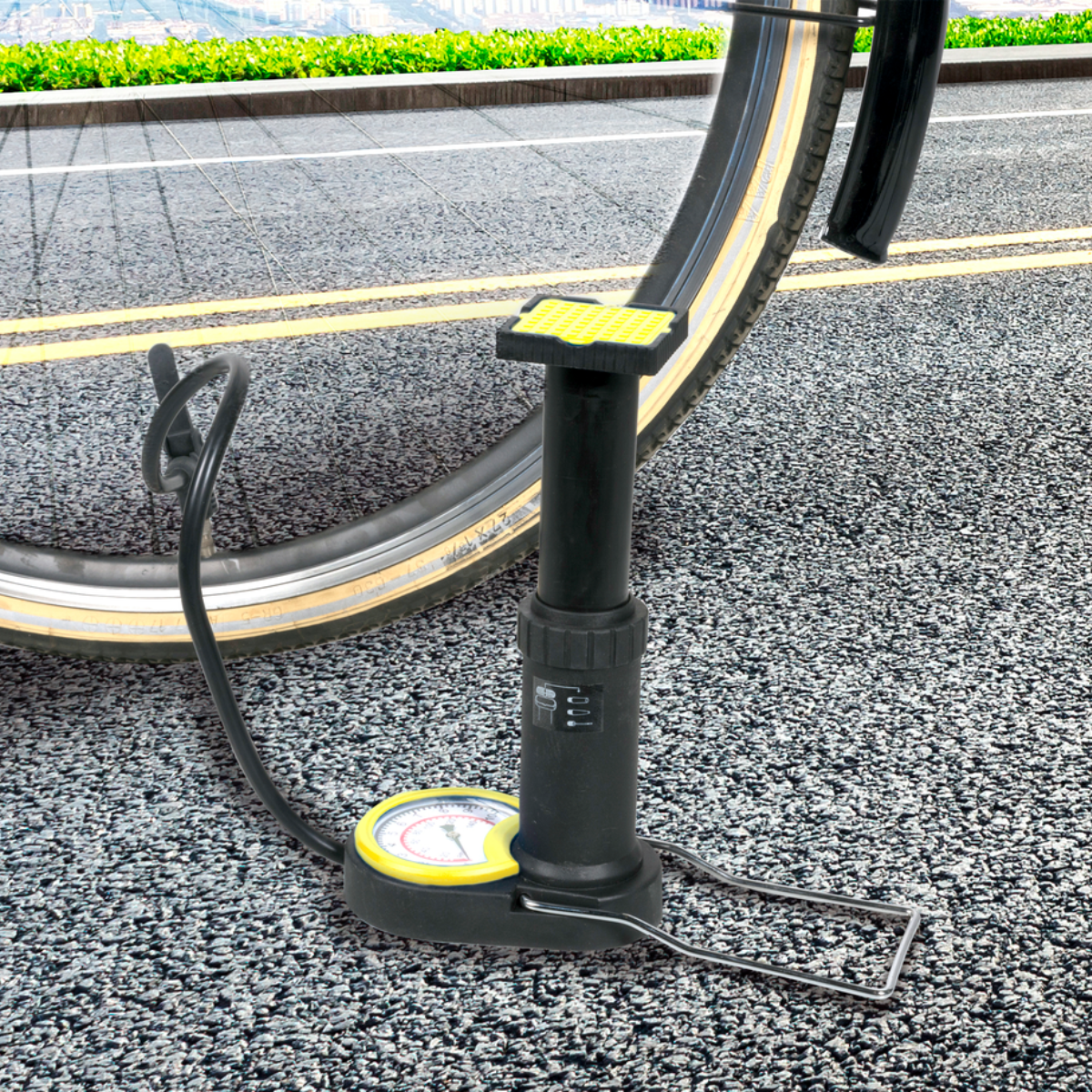 Eine schwarze Fahrradpumpe mit Manometer, abgewinkelt auf einen Fahrradreifen auf einer strukturierten Straße.