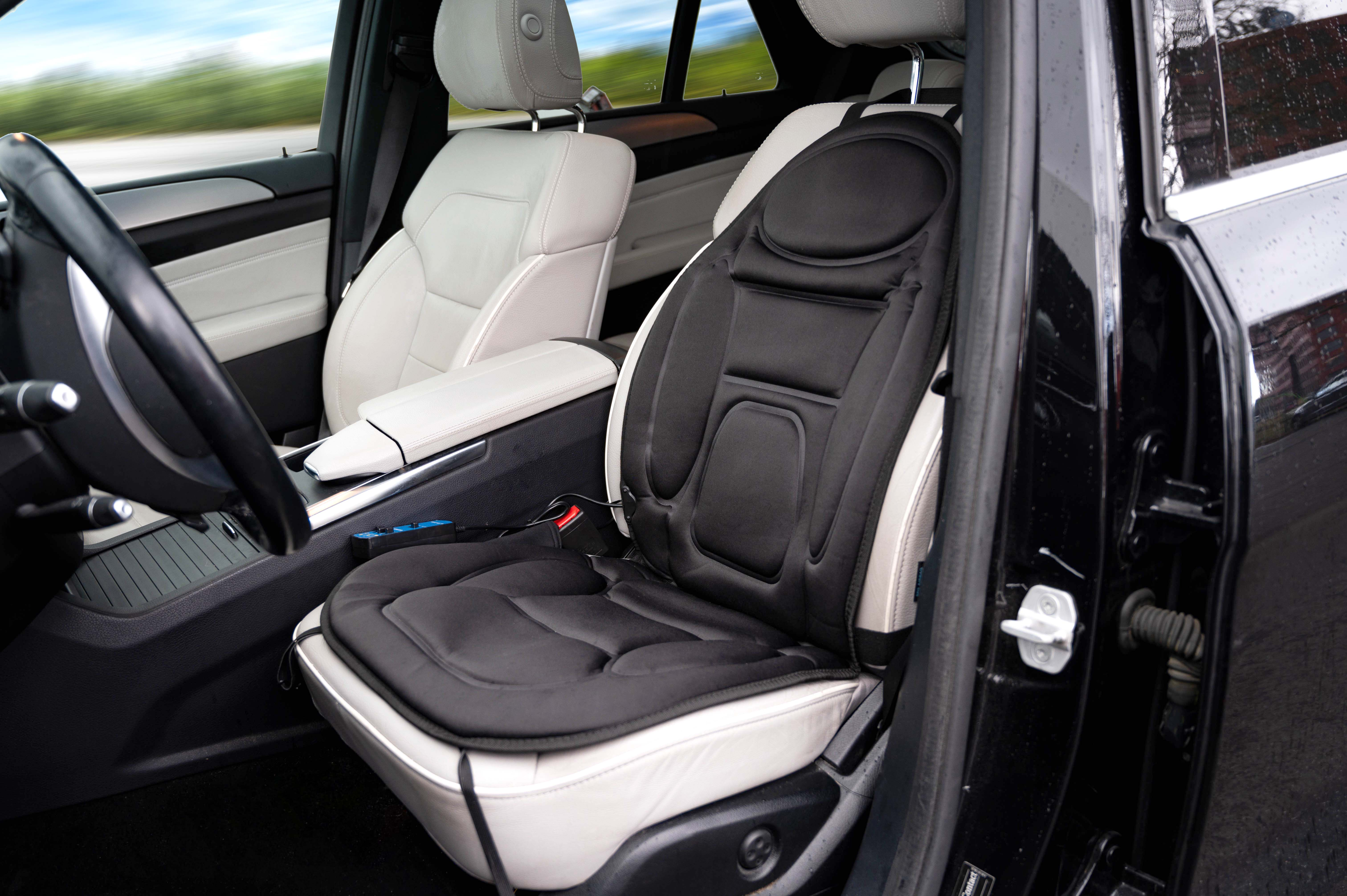 Auto-interieur met zwarte massagestoel. Stuur en dashboard zijn zichtbaar.