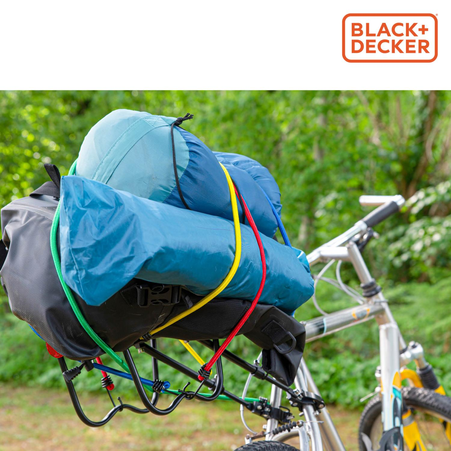 Een fiets met een rek met blauwe en grijze kampeerspullen, vastgezet met elastische koorden.