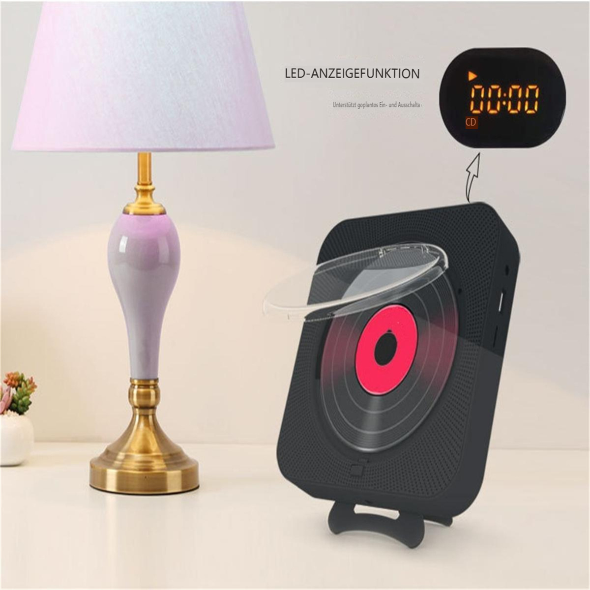 Ein kleiner CD-Player mit digitaler Uhranzeige auf einem Tisch, neben einer Lampe.