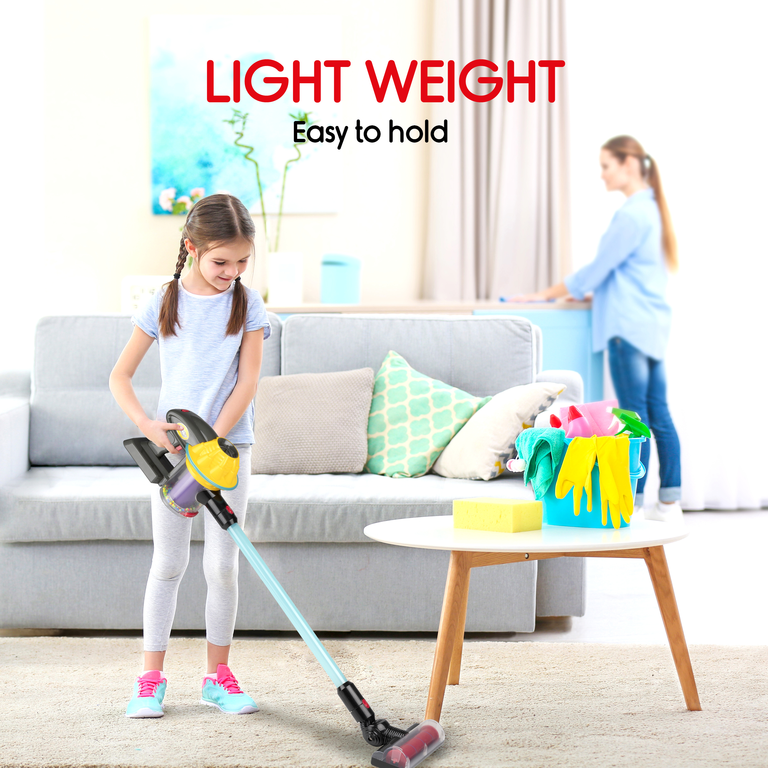 A girl vacuums a rug. A woman is in the background near a table with cleaning items.