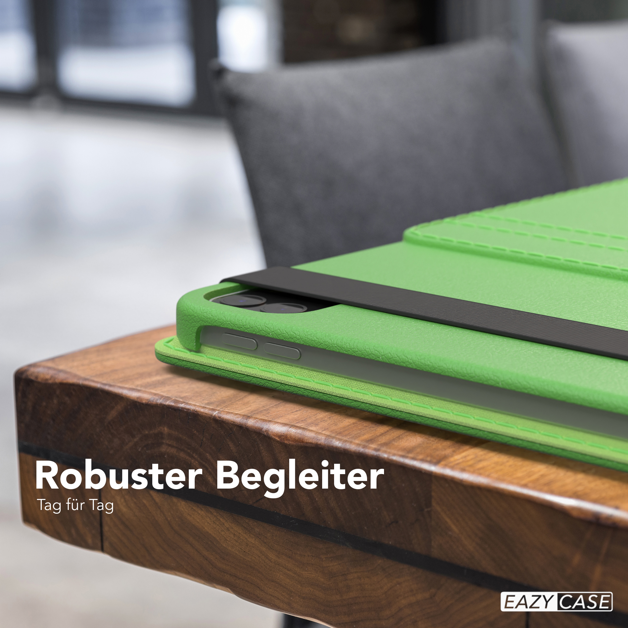 Grüne iPad-Hülle auf einem Holztisch. Im Hintergrund ein Stuhl.