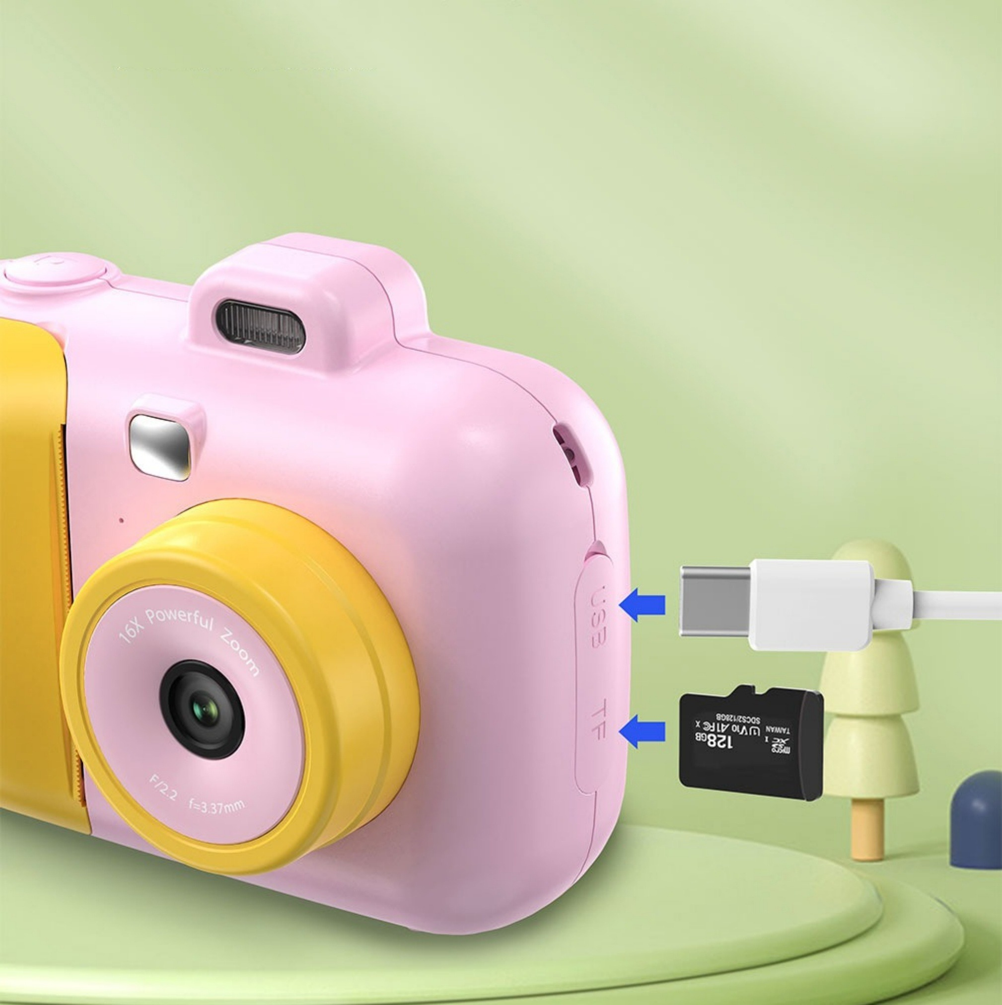 Eine rosa Kamera mit gelbem Oberteil, USB-Anschluss und Speicherkartensteckplatz, mit USB-Kabel.