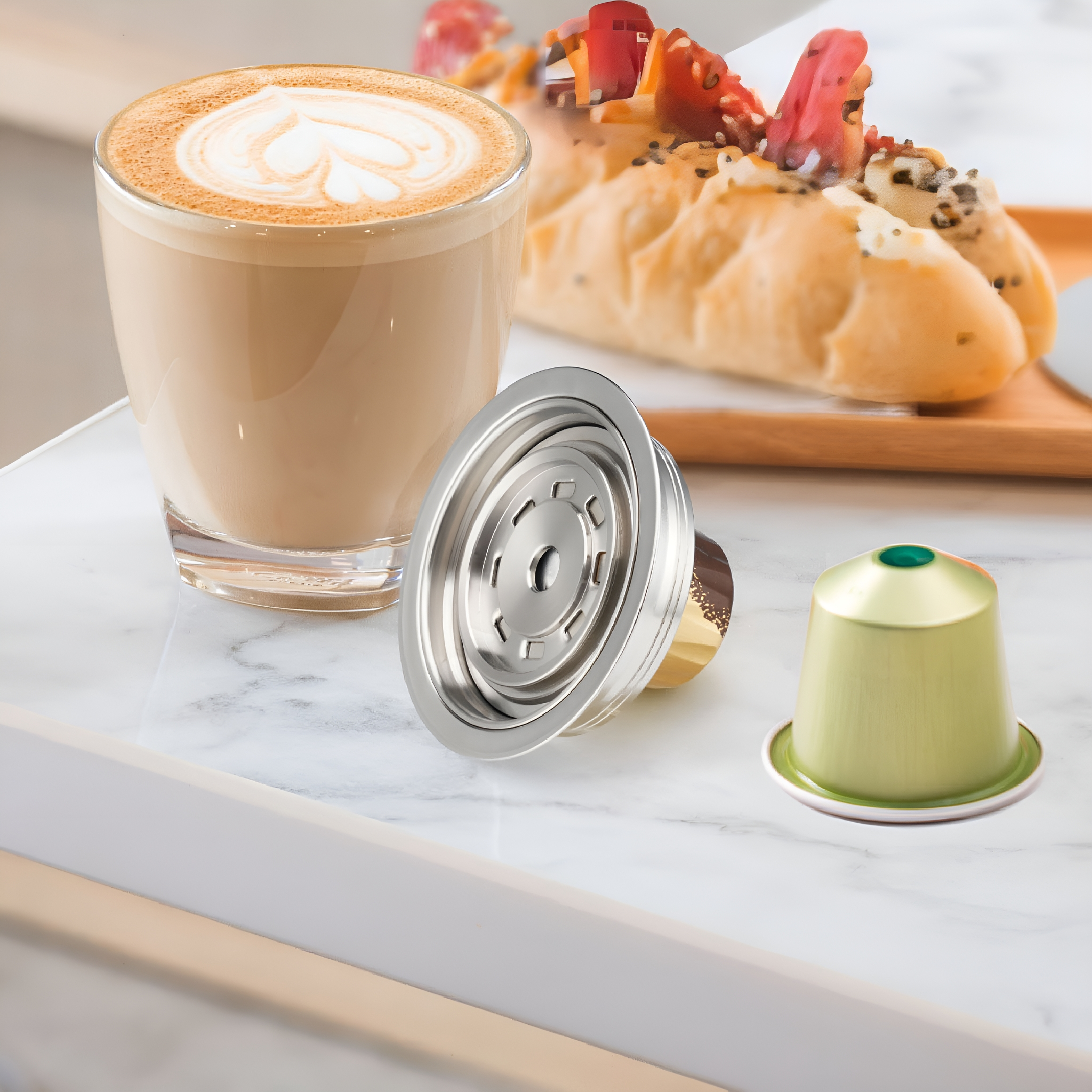 Kaffee mit Latte Art, Croissant und Kaffeekapseln auf einem Tablett.