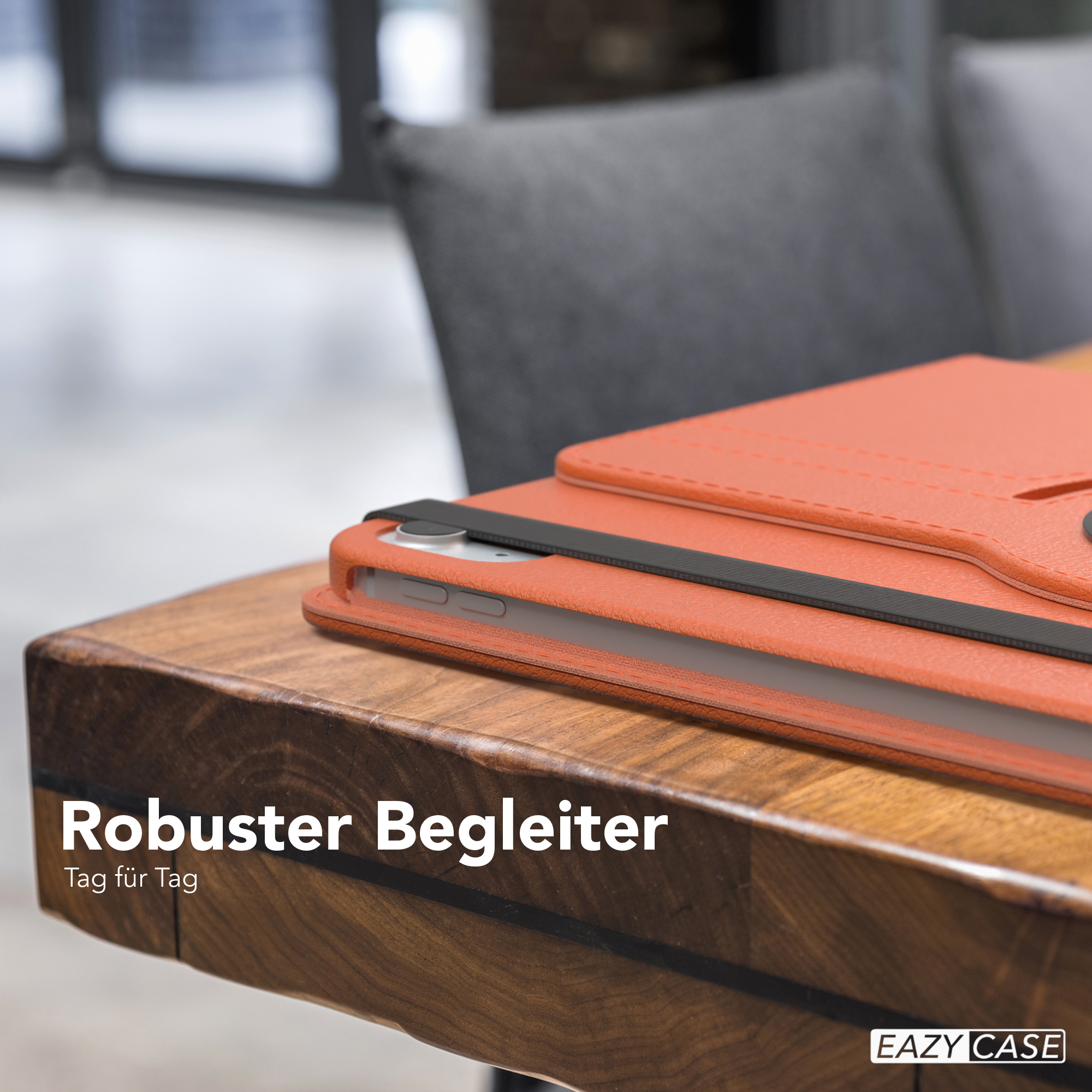 Orangefarbene Tablethülle auf einem Holztisch. Ein Stuhl ist im Hintergrund.