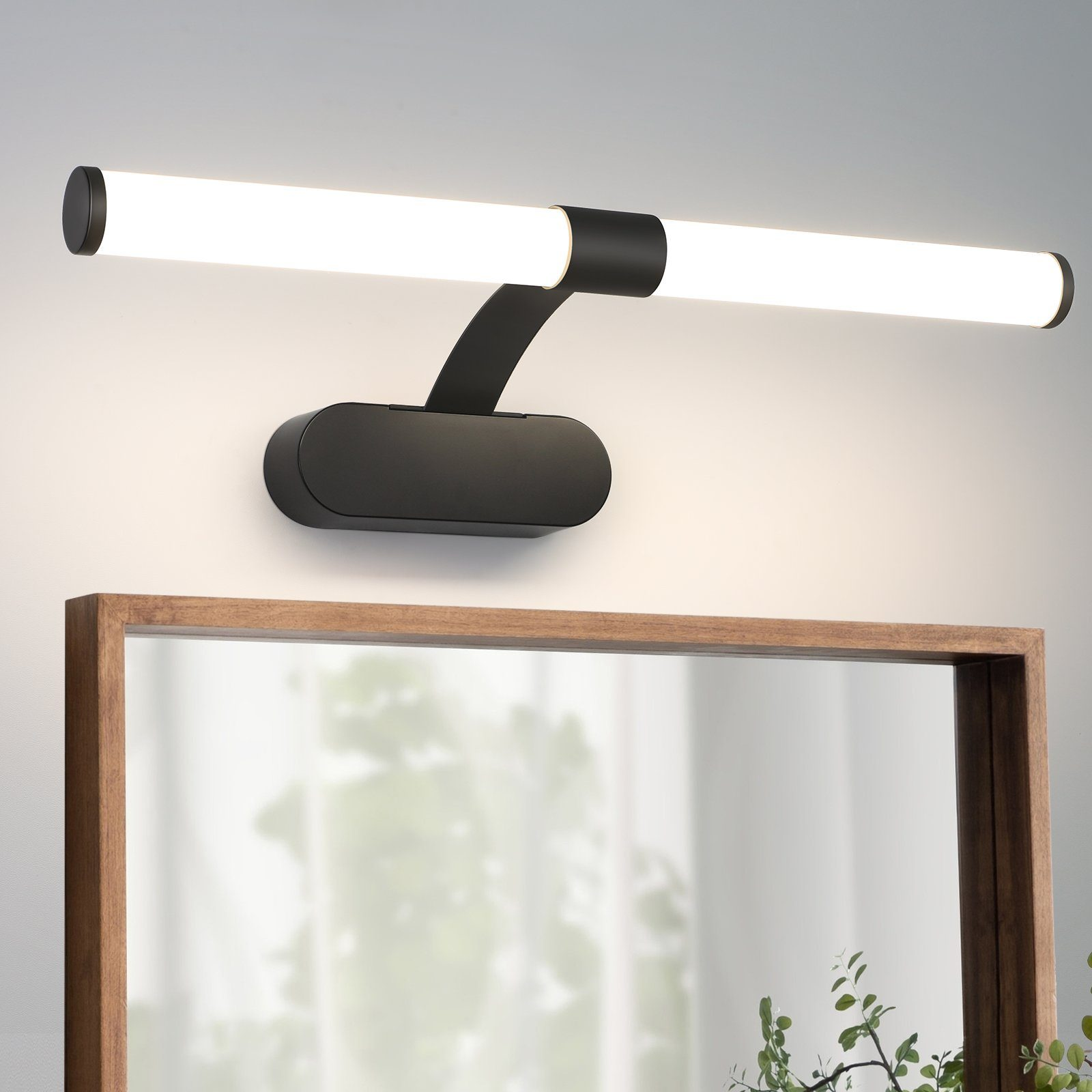 Apparecchio di illuminazione per bagno nero. Uno specchio e una pianta sullo sfondo.