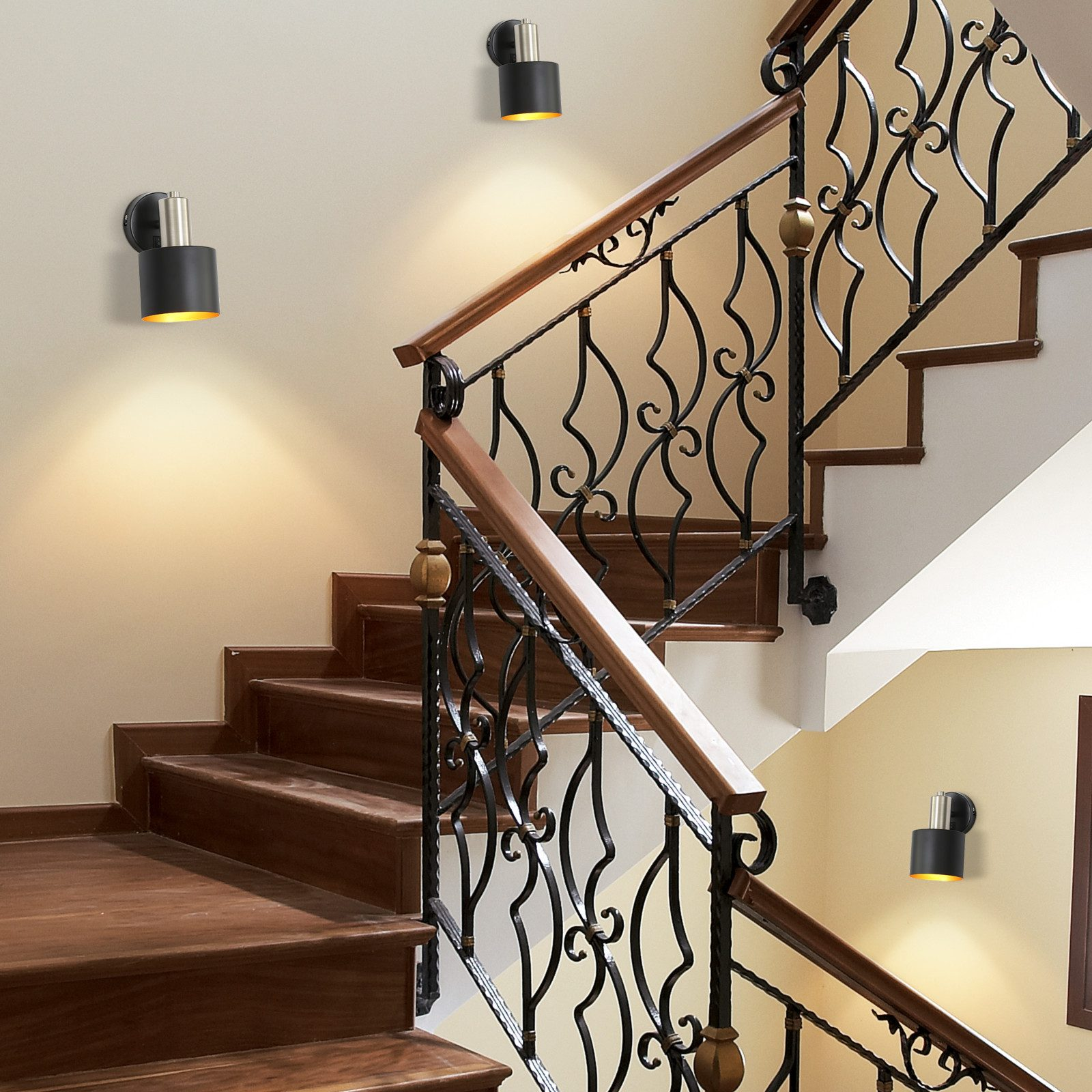 Scala con luci a parete. Le luci sono cilindri neri con anelli interni dorati.