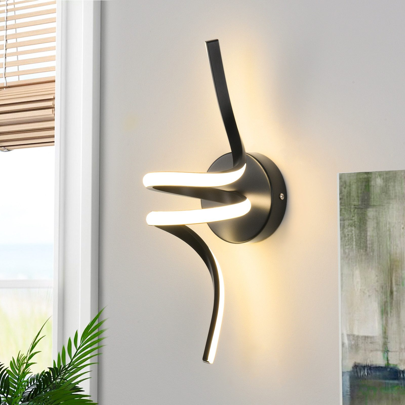 Lámpara de pared moderna negra con diseño curvo, emite luz cálida. Montada en pared blanca cerca de una ventana.