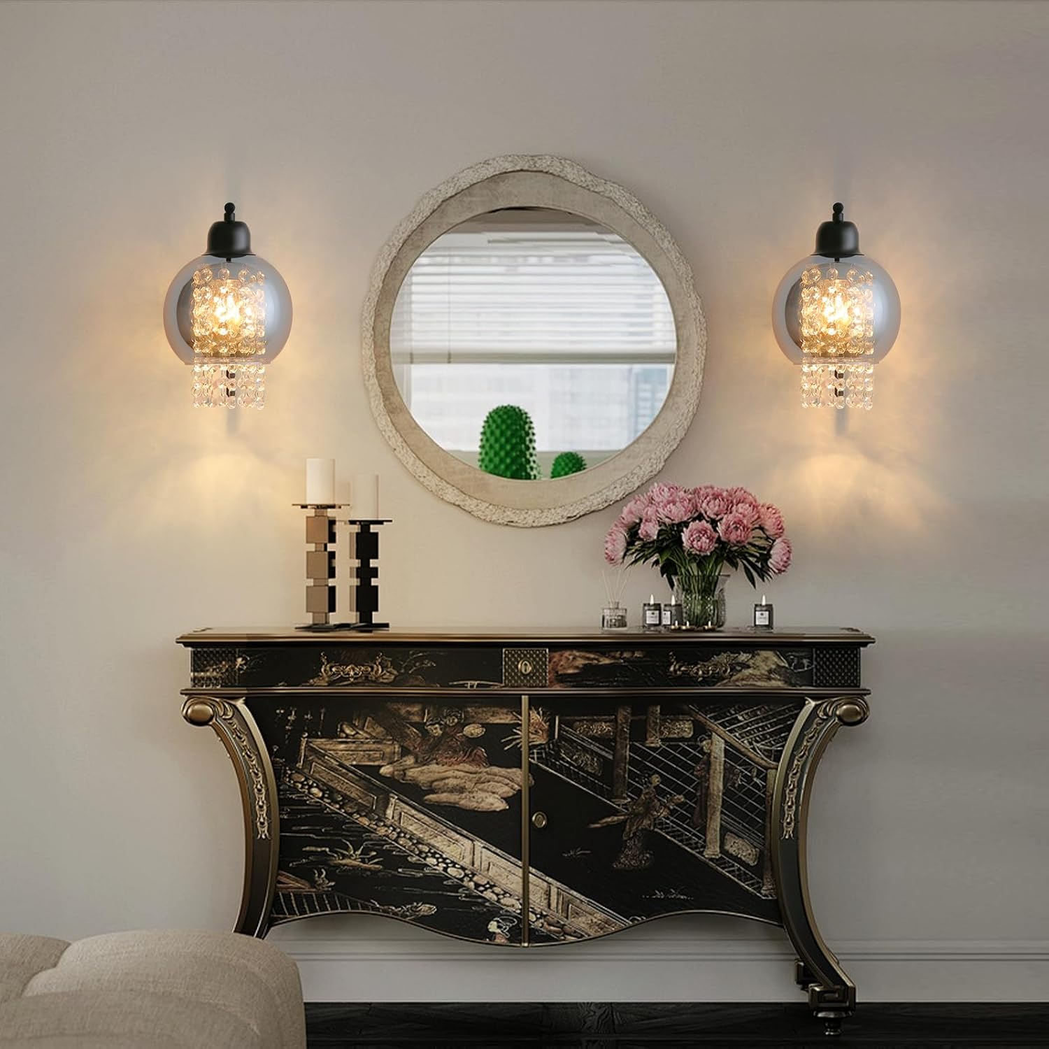 Un muro con uno specchio, due lampade e un mobile. Fiori, candele e decorazioni sono presenti.