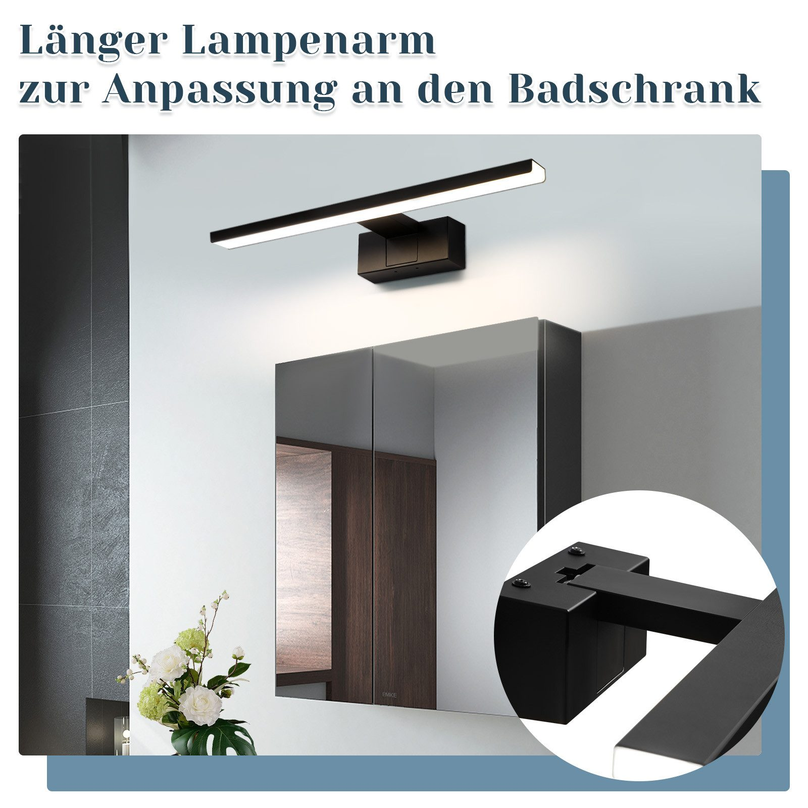 Badezimmerspiegel mit schwarzer Lampe darüber. Schwarzer Schrank darunter, eine Vase mit Blumen.