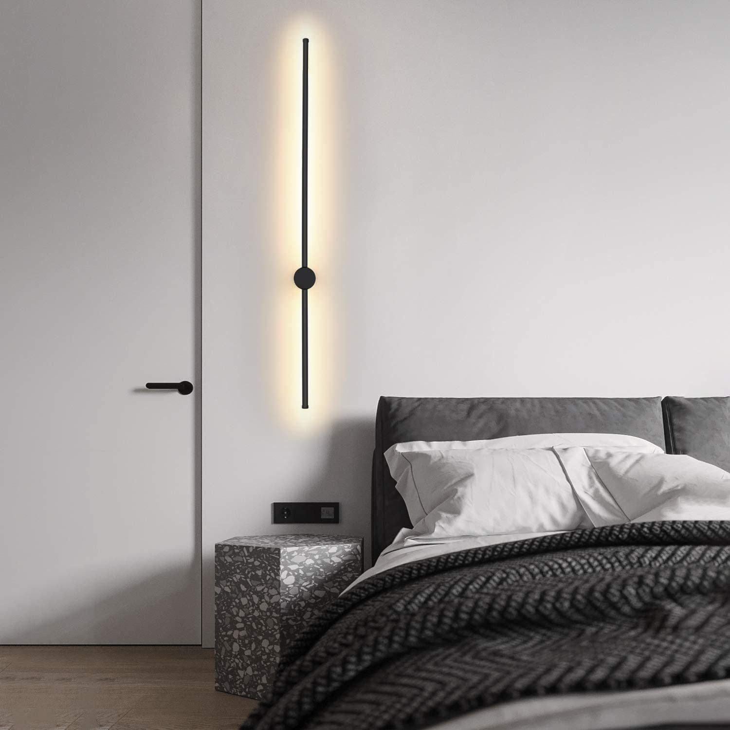 Camera da letto con un'apparecchio di illuminazione verticale nero, un letto e un comodino.