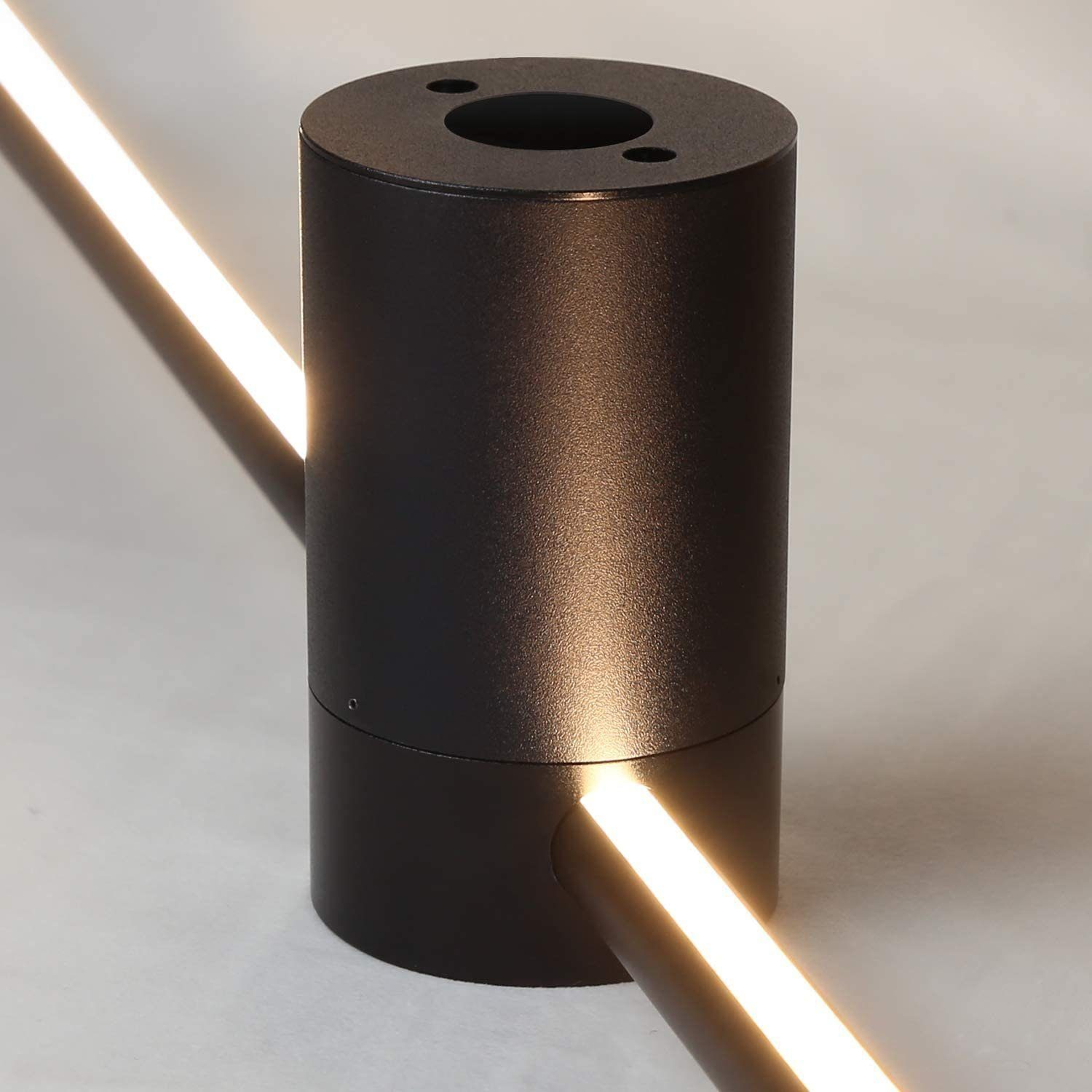 Apparecchio di illuminazione cilindrico nero con una striscia luminosa. La luce brilla dal lato del cilindro.