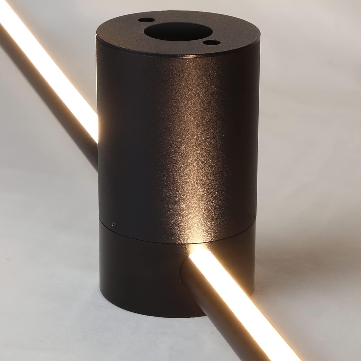 Un apparecchio di illuminazione cilindrico nero con un raggio di luce che si estende lungo una superficie.
