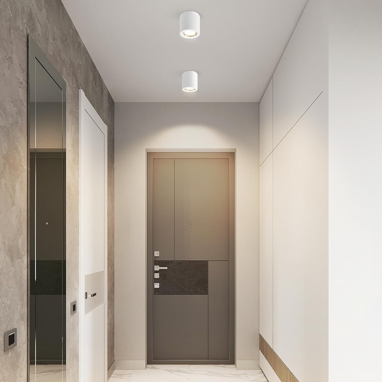 Pasillo con paredes blancas, dos luces de techo, una puerta gris y una pared tipo mármol. El suelo es claro.