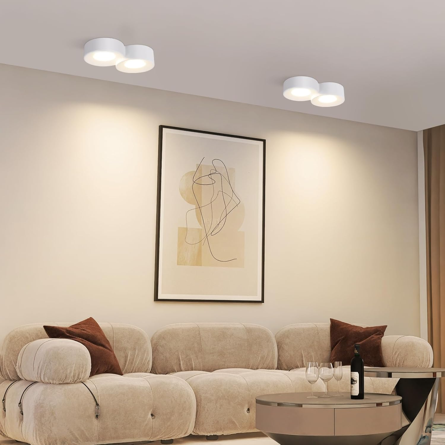 Luces de techo blancas en una sala de estar moderna con un sofá beige y obras de arte en la pared.