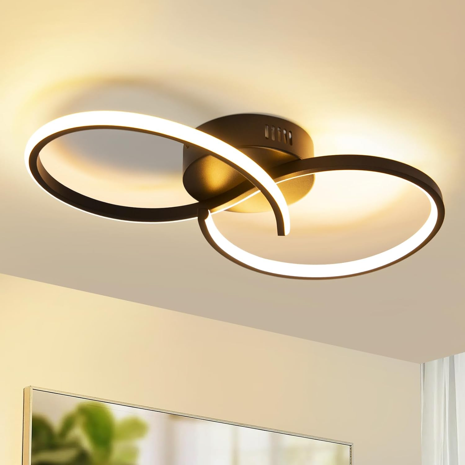 Luz de techo con dos anillos de luz blancos curvos. Base central negra. La luz está encendida.