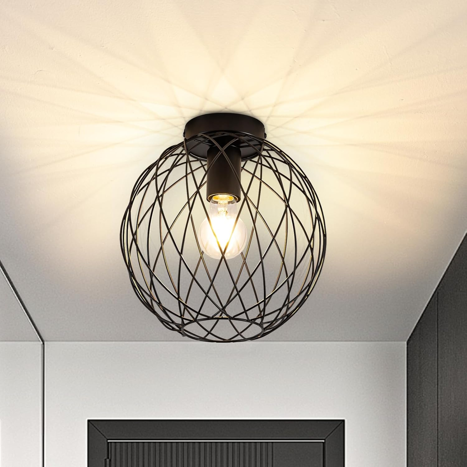 Eine schwarze Drahtkäfig-Leuchte, die von einer weißen Decke mit einer Glühbirne hängt.