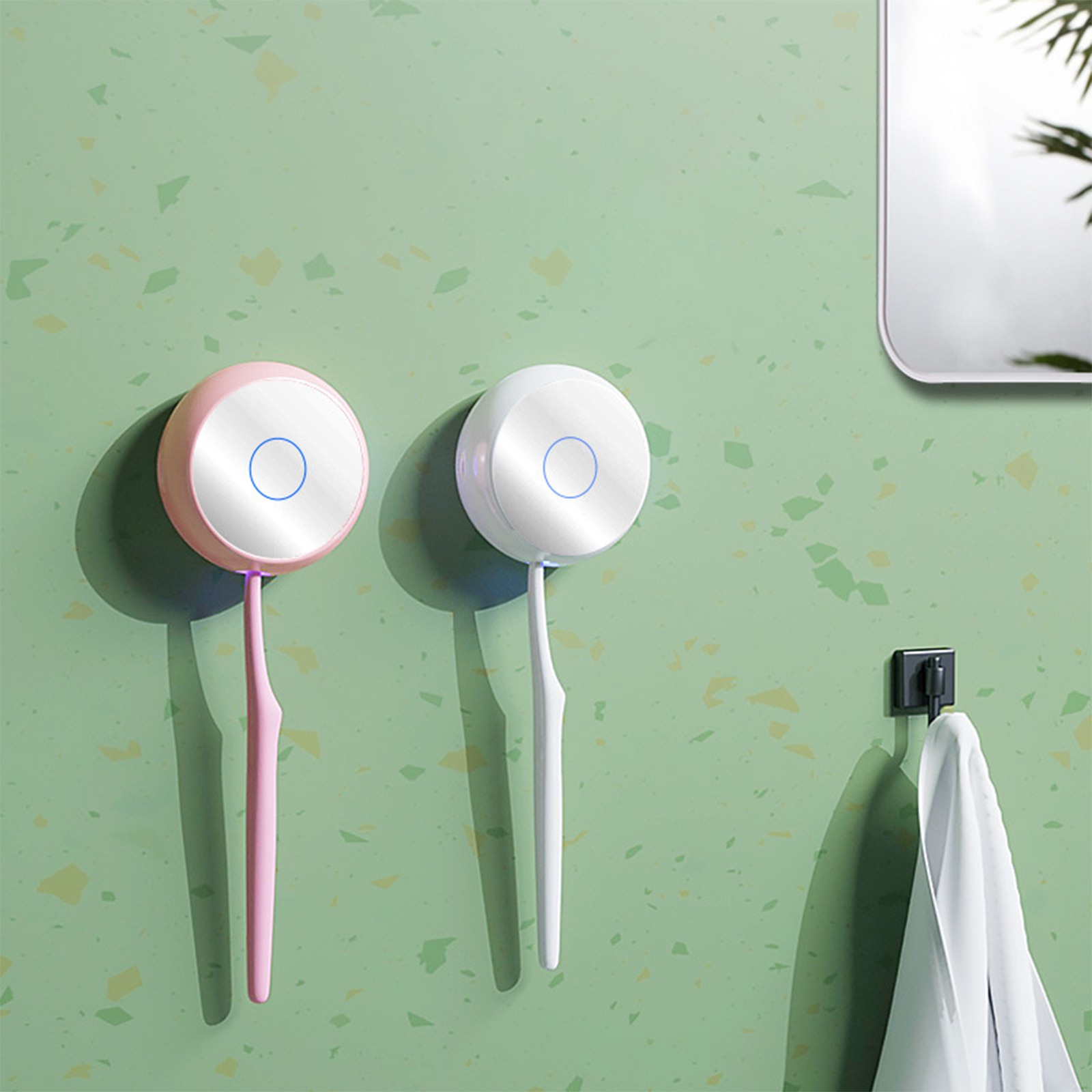 Zwei elektrische Zahnbürsten an einer grünen Wand, eine rosa und eine weiß.