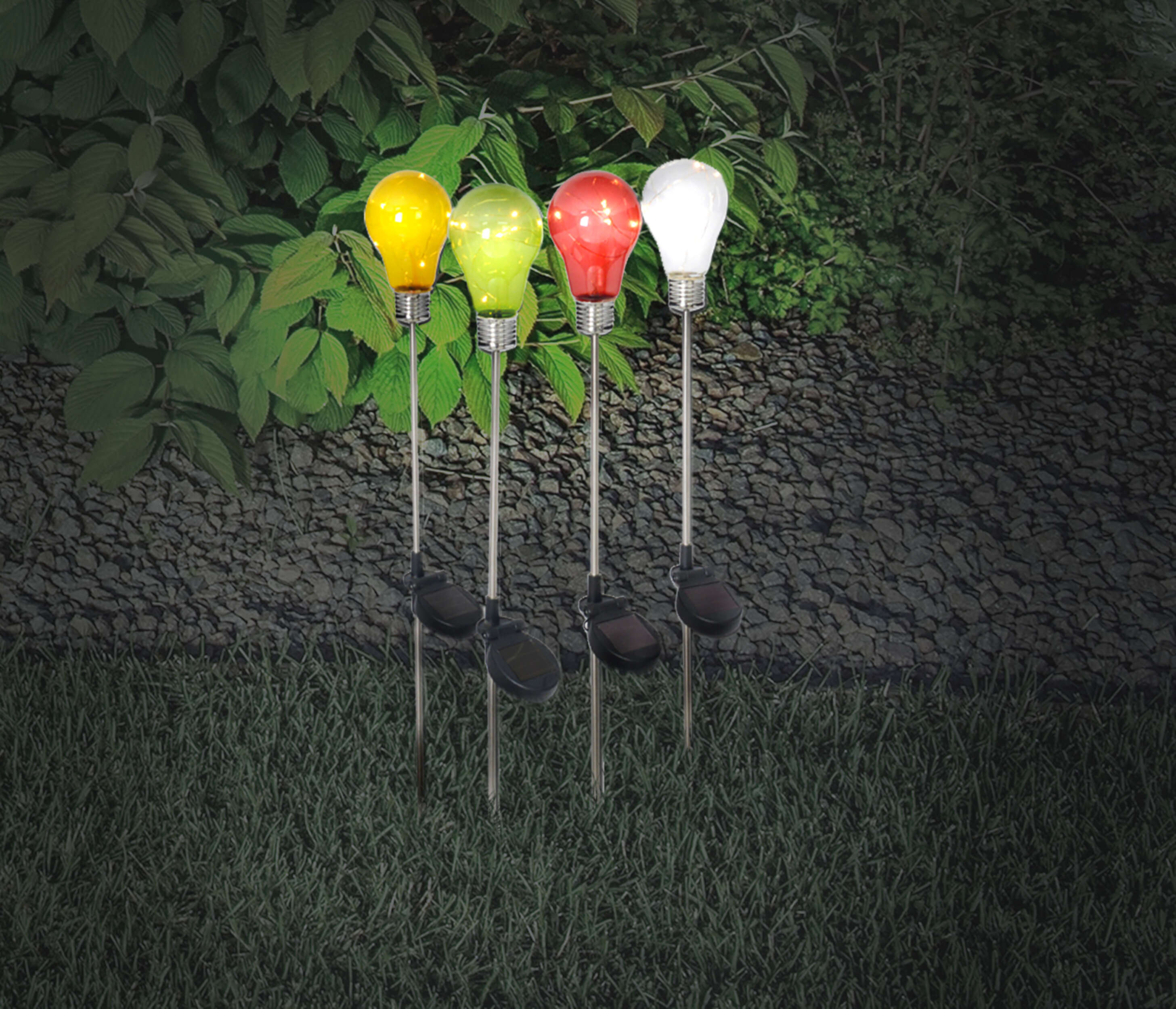Vier bunte Glühbirnen in einem Garten. Sie sind gelb, grün, rot und weiß.