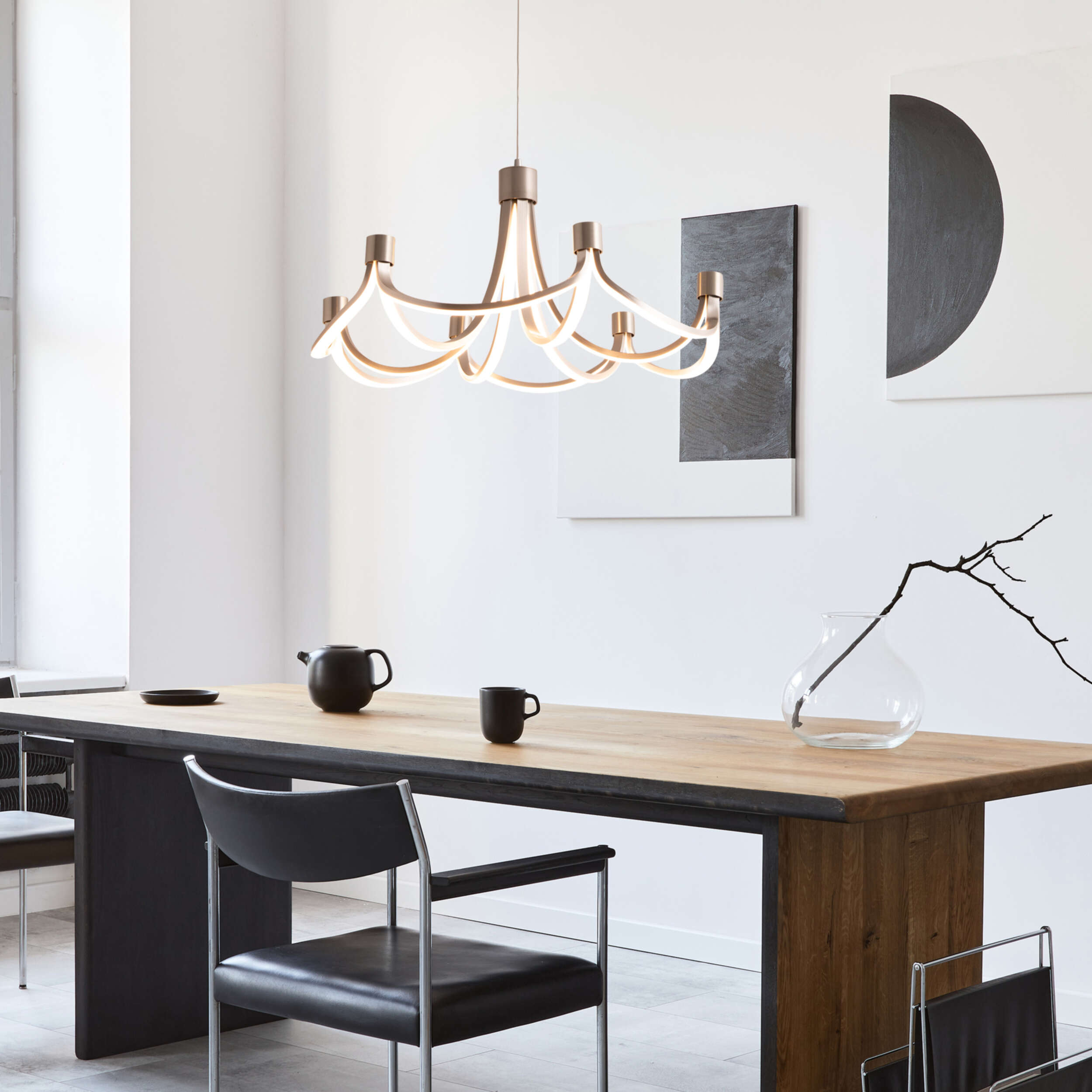 Modernes Esszimmer mit Kronleuchter, langem Holztisch und Kunstwerk an der Wand.
