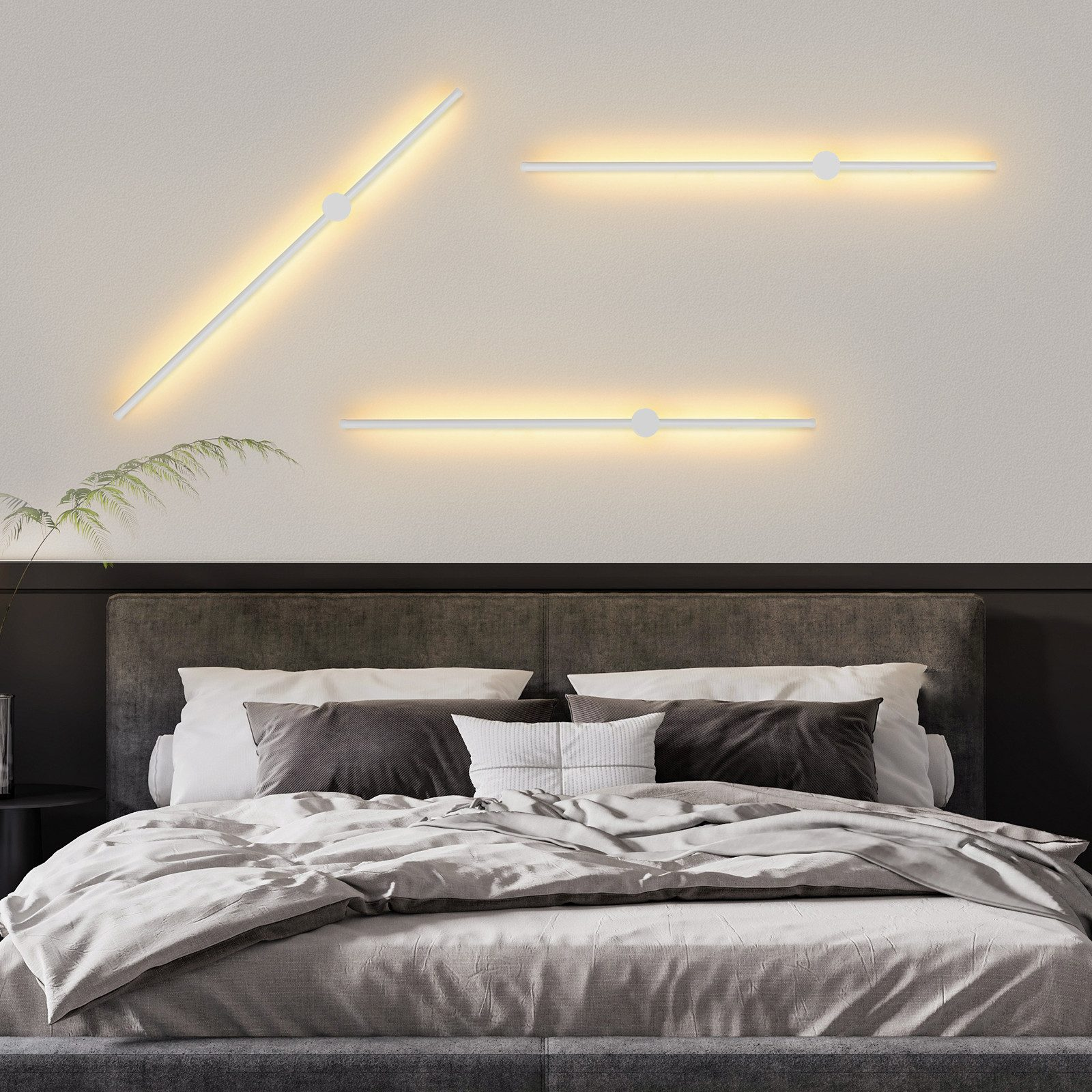 Lampade da parete moderne sopra un letto. Le luci sono bianche e hanno un design minimalista.