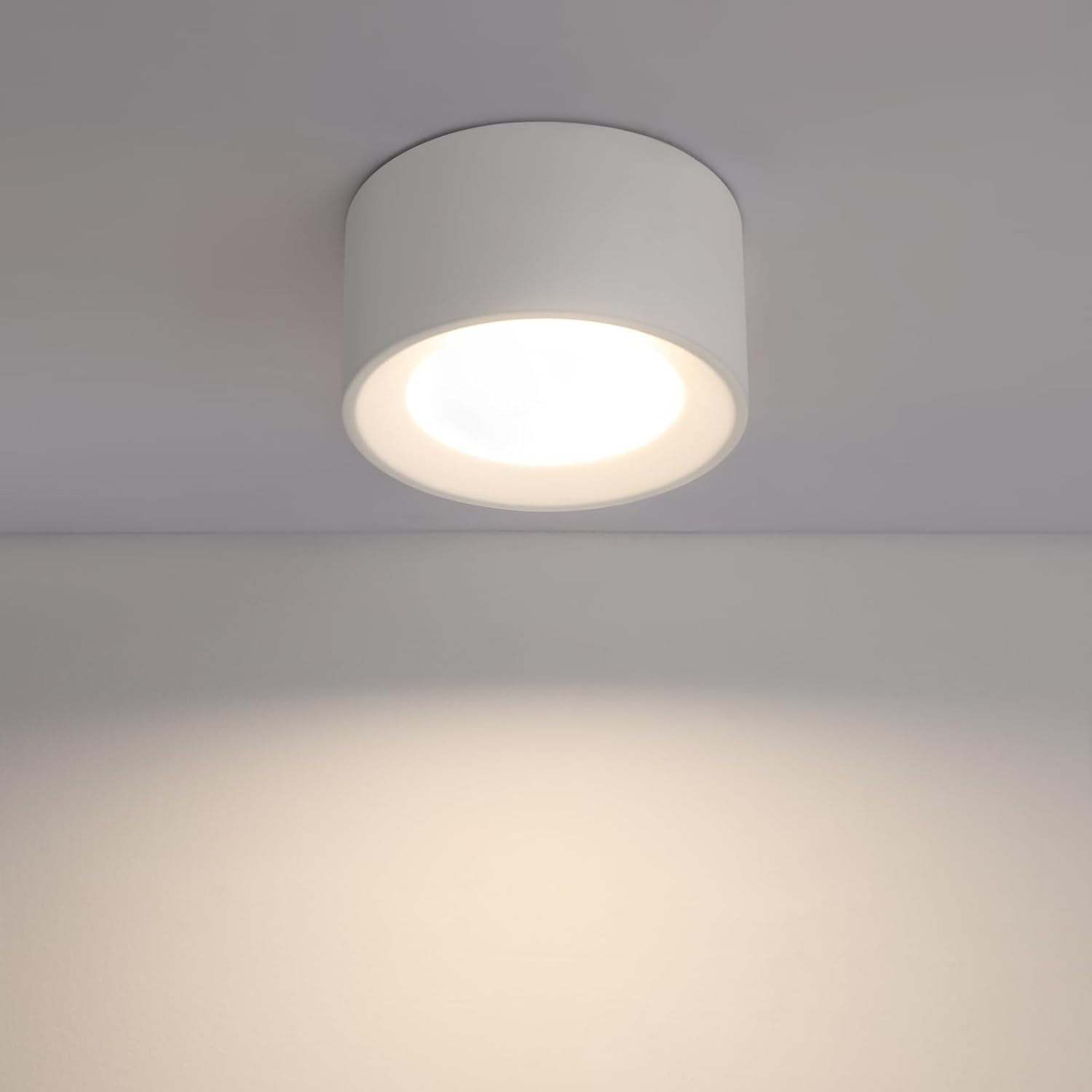 Una lámpara de techo cilíndrica blanca que emite luz brillante hacia abajo. Diseño limpio y sencillo.