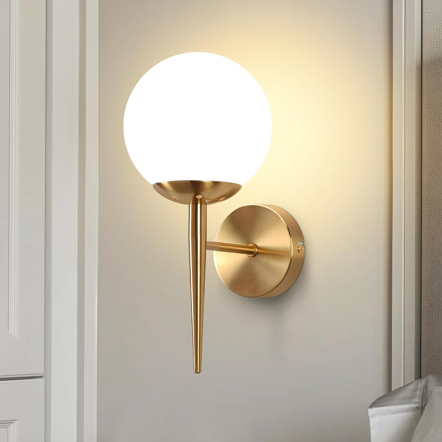 Lámpara de pared dorada con pantalla de globo blanco, montada en pared gris claro.
