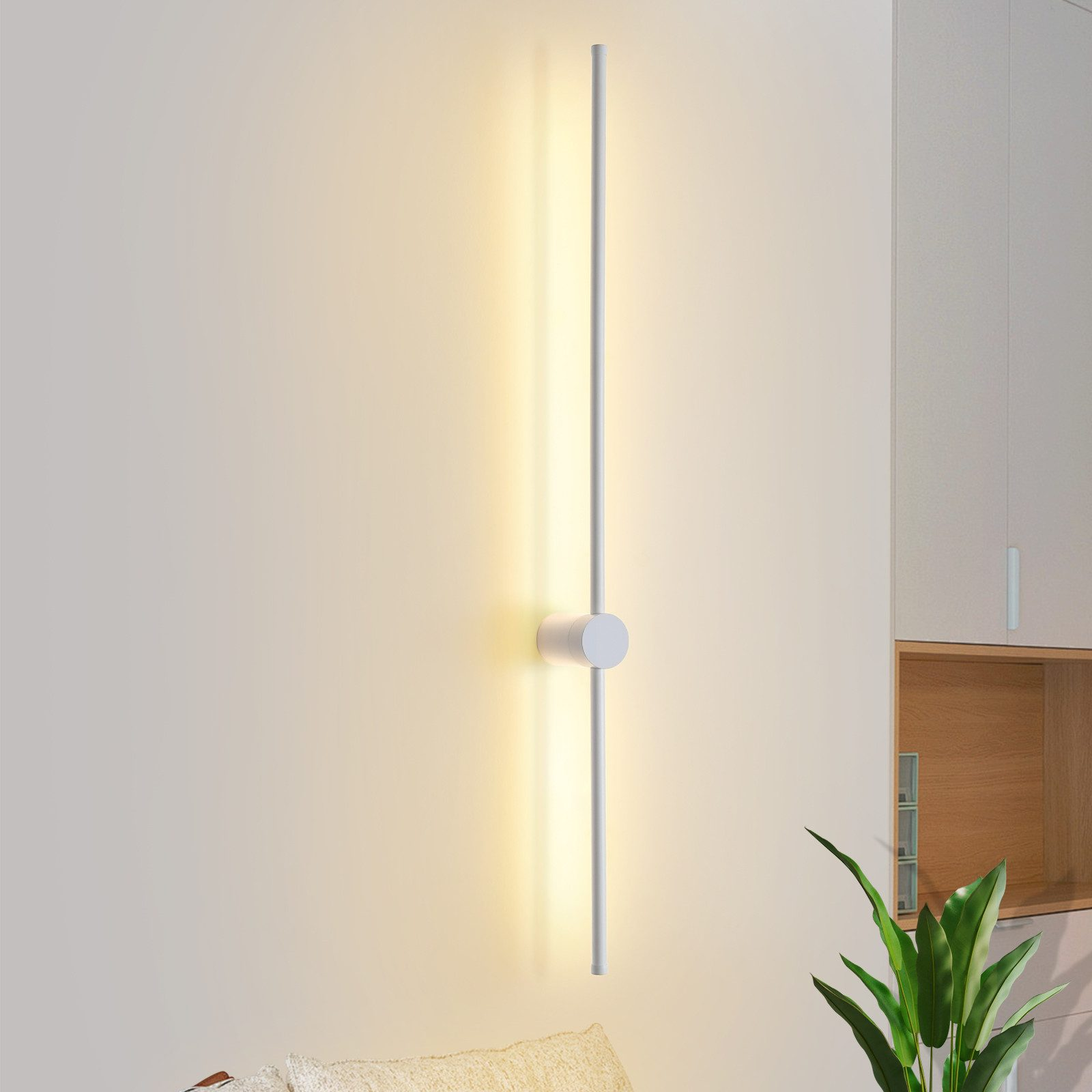 Un lungo apparecchio di illuminazione verticale che emette luce contro un muro bianco.