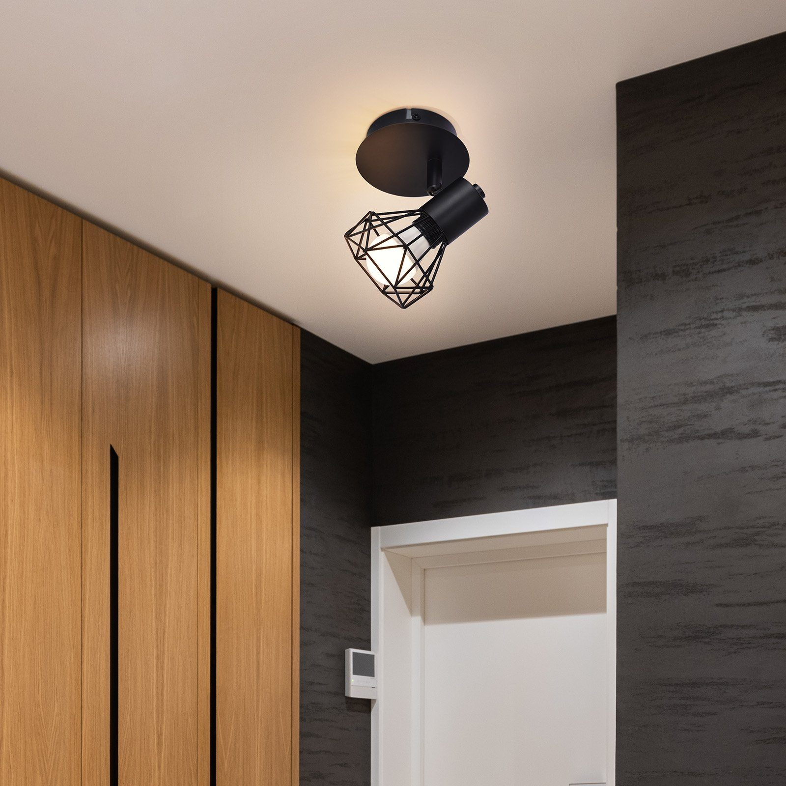 Un moderno faretto da soffitto con un design a gabbia nera, che illumina un corridoio.
