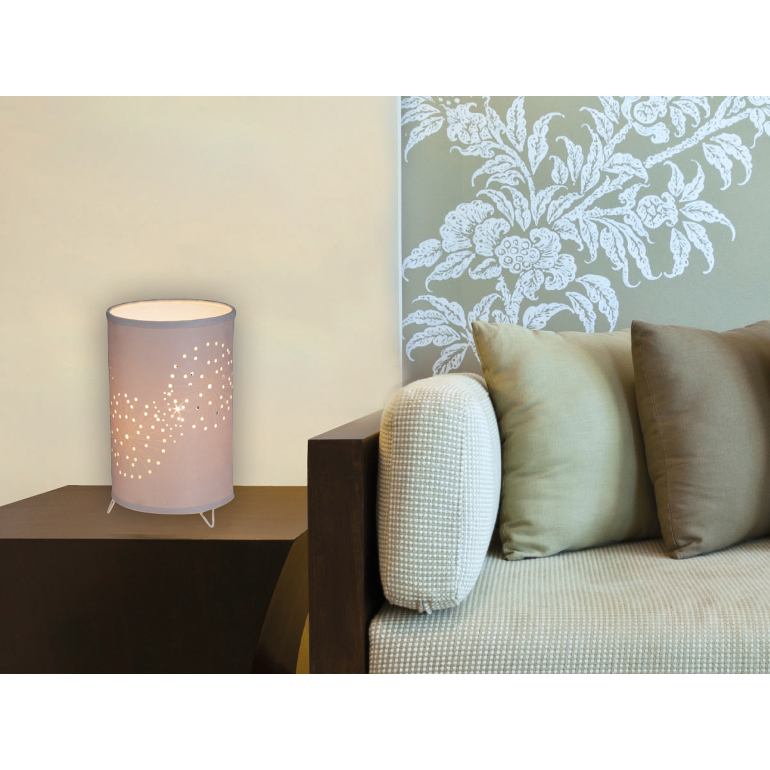 Eine Lampe mit einem zylindrischen Schirm mit Muster, neben einem Sofa und einer Wand.