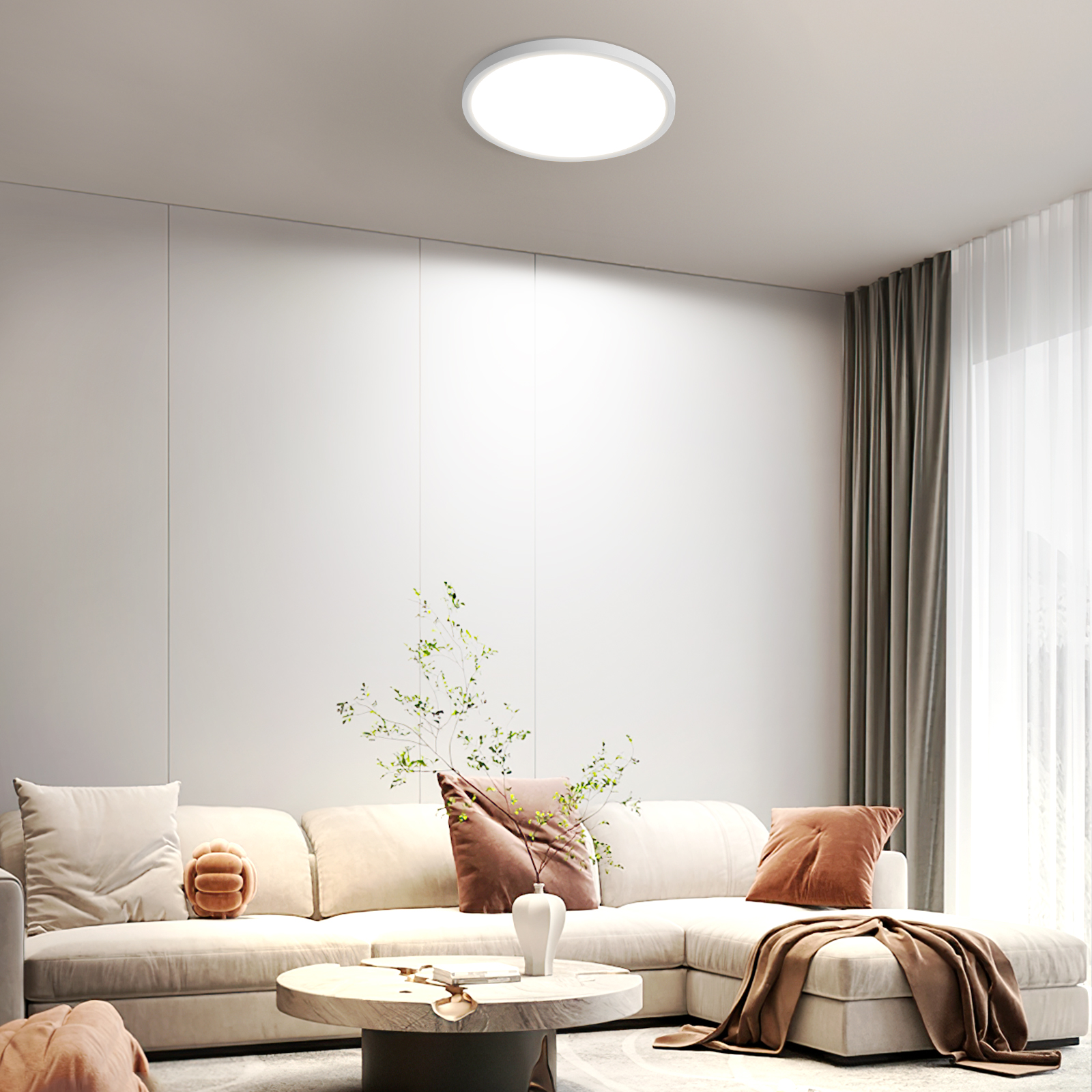 Una sala de estar con un sofá blanco, una mesa de centro, una luz de techo redonda y plantas.