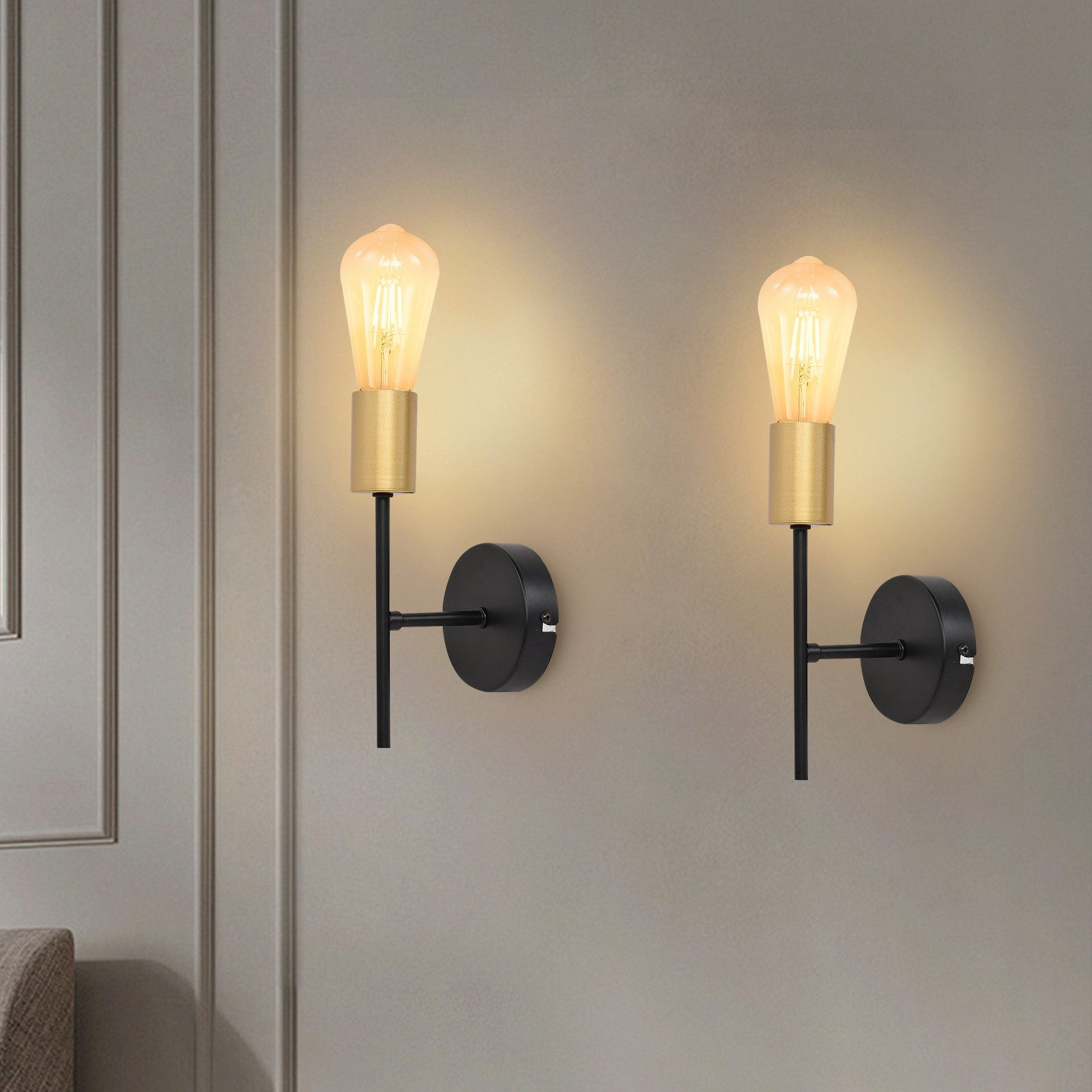 Due luci da parete con lampadine Edison e elementi neri, montate su un muro grigio.