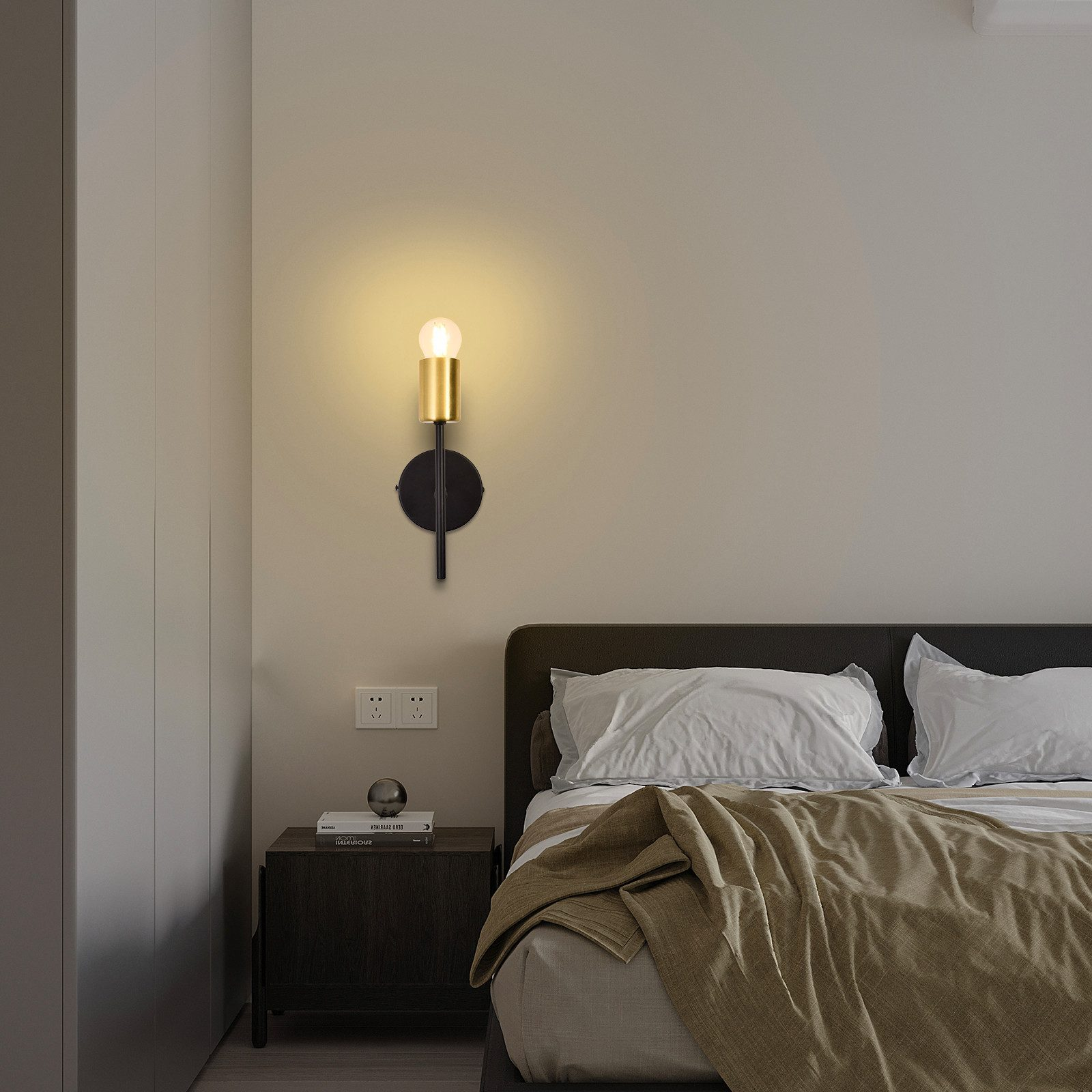 Applique con base nera e lampada dorata. Letto sullo sfondo.