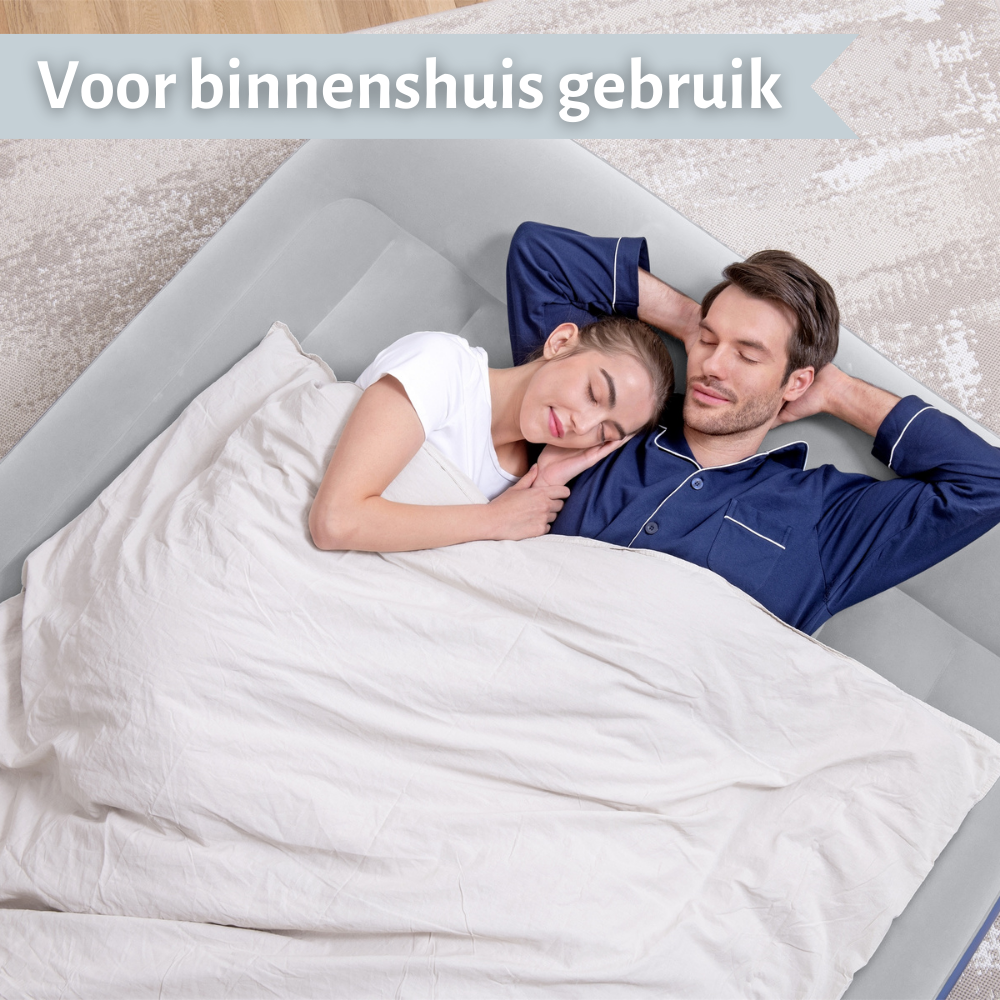 Een stel slaapt op een lichtgrijze opblaasmatras in een kamer. Ze zijn bedekt met een witte deken.