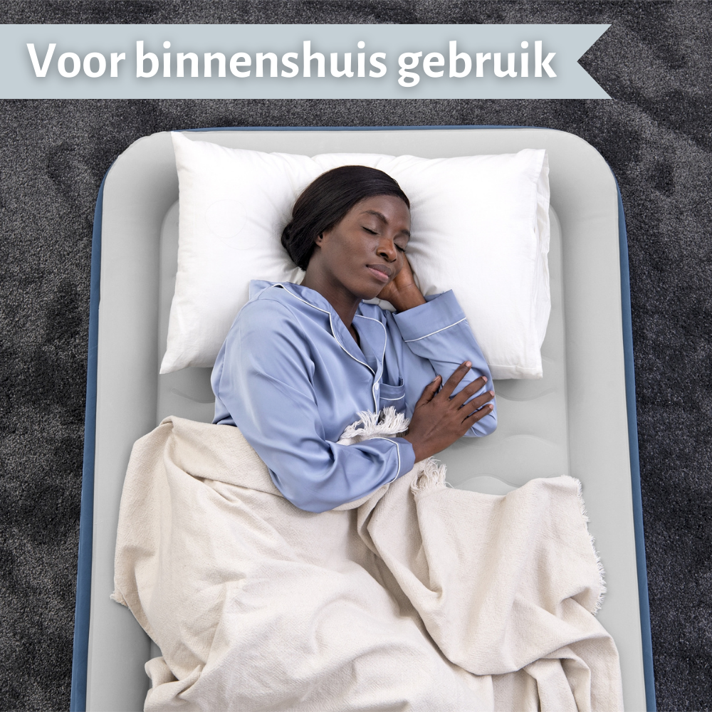 Een vrouw slaapt op een grijs luchtbed met een wit kussen en deken. Tekst: "Voor gebruik binnenshuis".