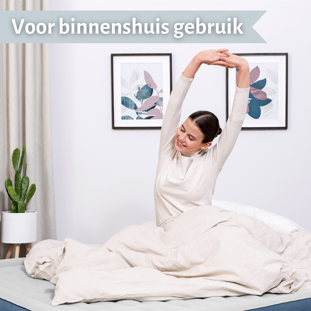 Vrouw die zich uitrekt op een opblaasmatras. Binnenomgeving, naast een cactus en ingelijste wandkunst.